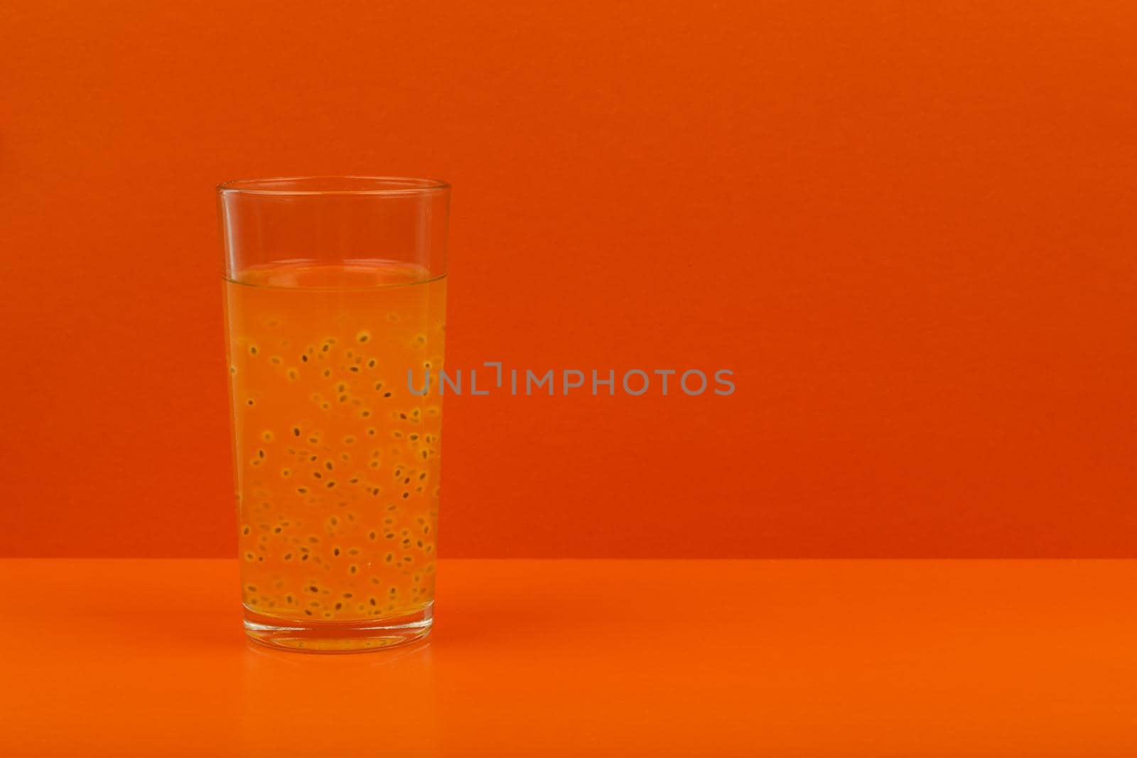 Fruit juice with passion fruit seed on orange background with space for text by Senorina_Irina