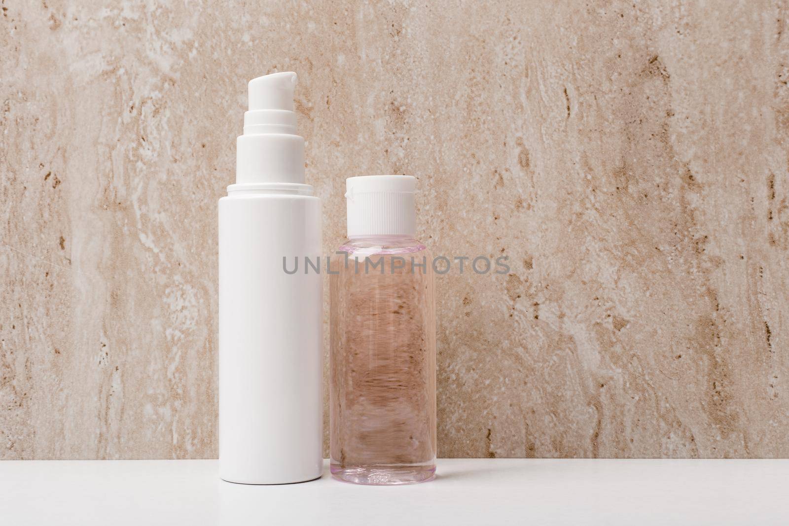 Two skincare products against marble background with a space for text