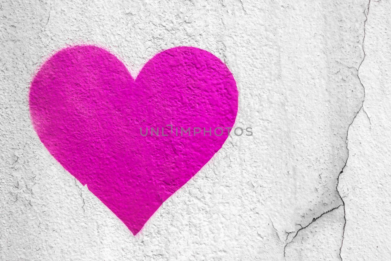 Pink love heart hand drawn on grungy wall. Textured background trendy street style.