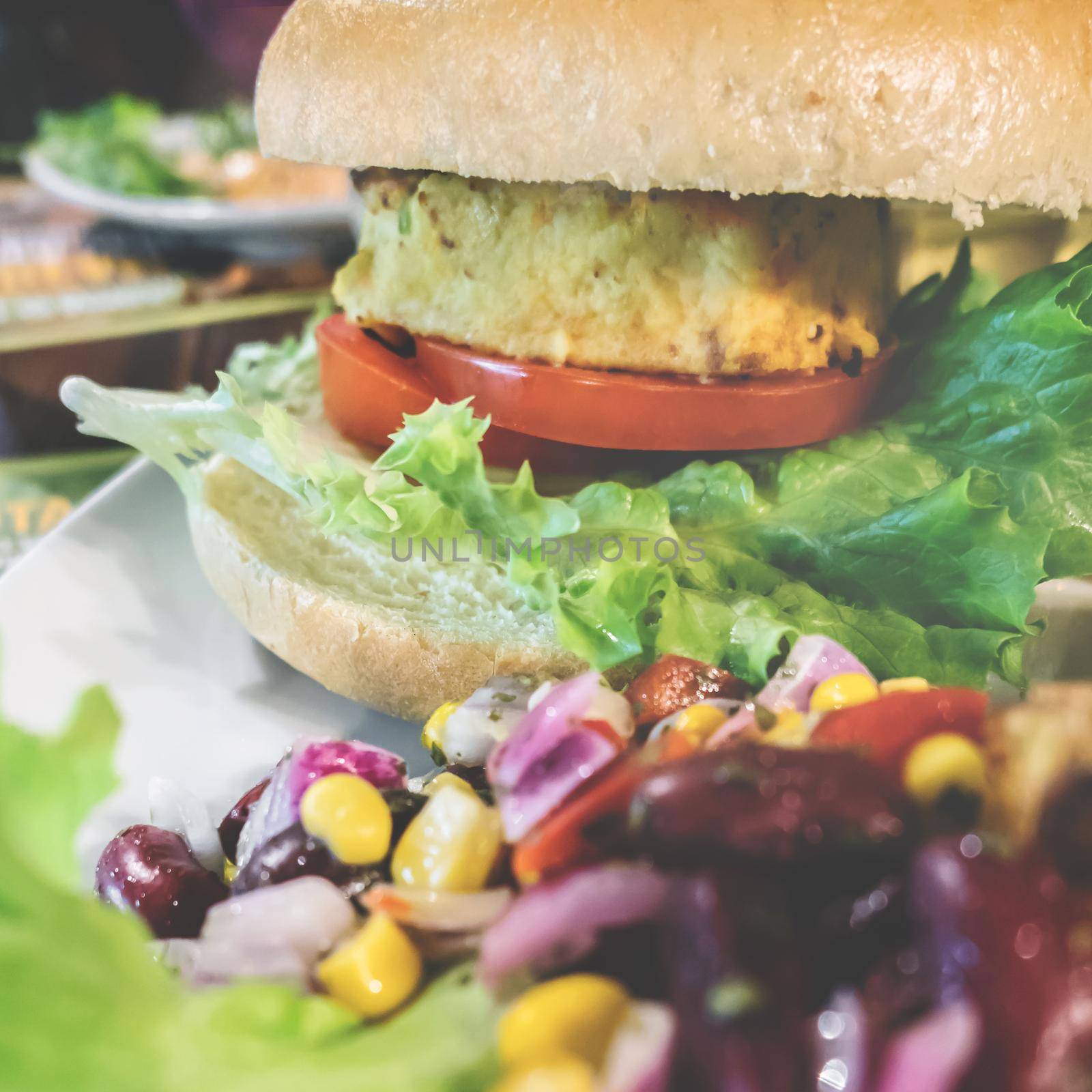 Vegan hamburger ready for consumption. Healthy and vegetarian life concept. Meatless snack based on soy with fresh vegetables. Shallow DOF. Close-up.