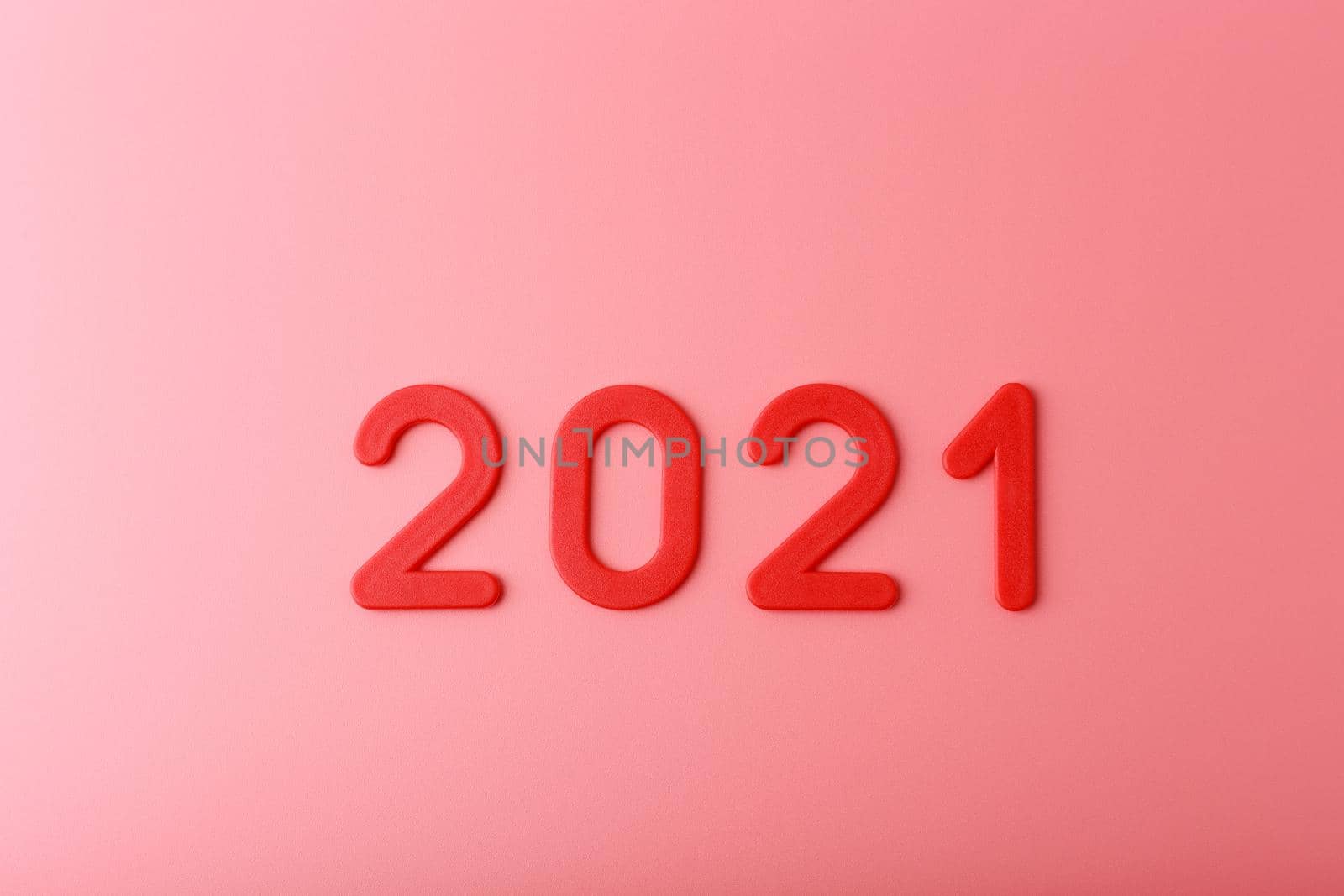 Top view of 2021 red plastic letters on bright pink background with light and shadow. Minimalistic concept of New Year and Christmas