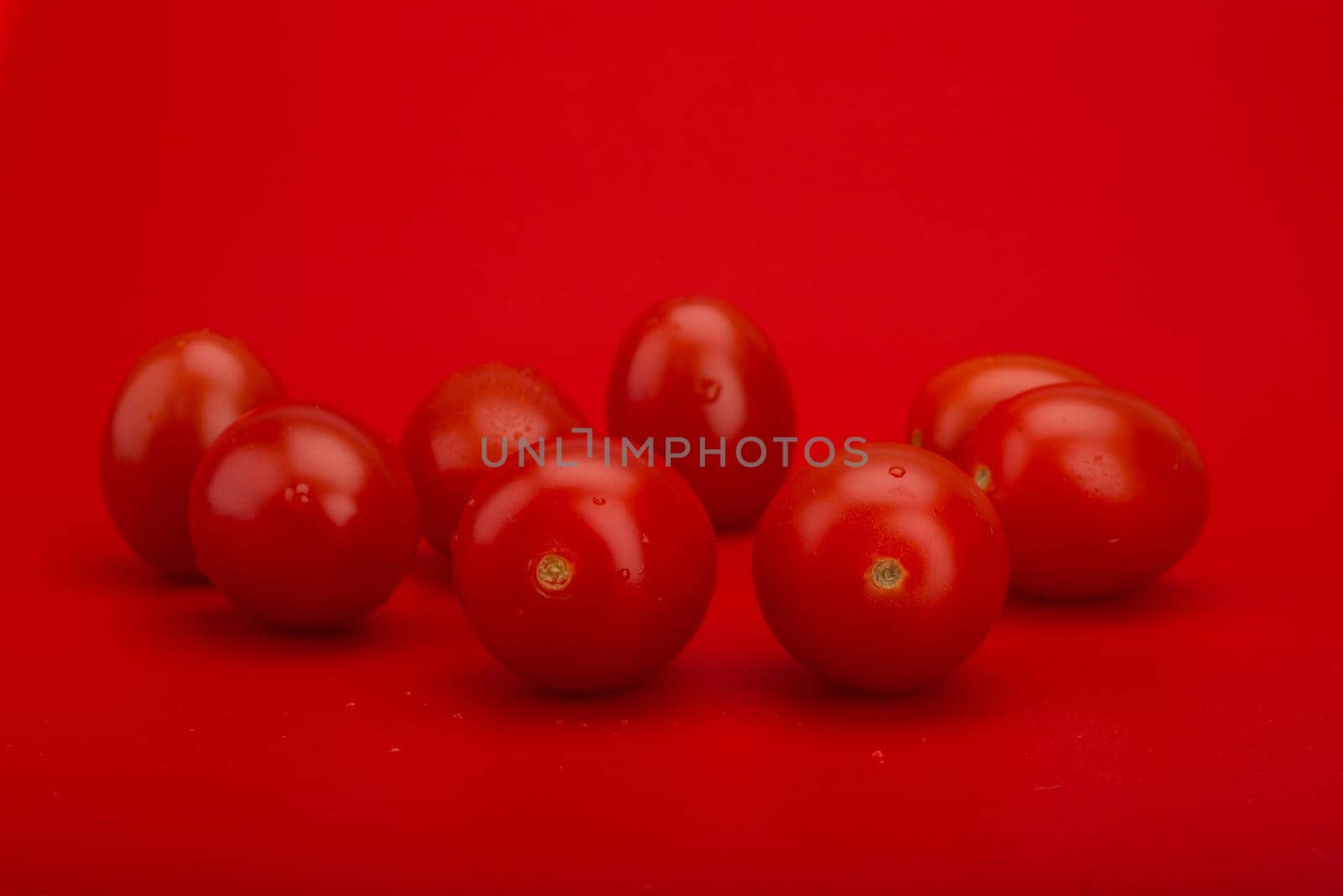 Bunch of wet tomatoes with drops of water on red background. Concept of vegan or healthy lifestyle by Senorina_Irina