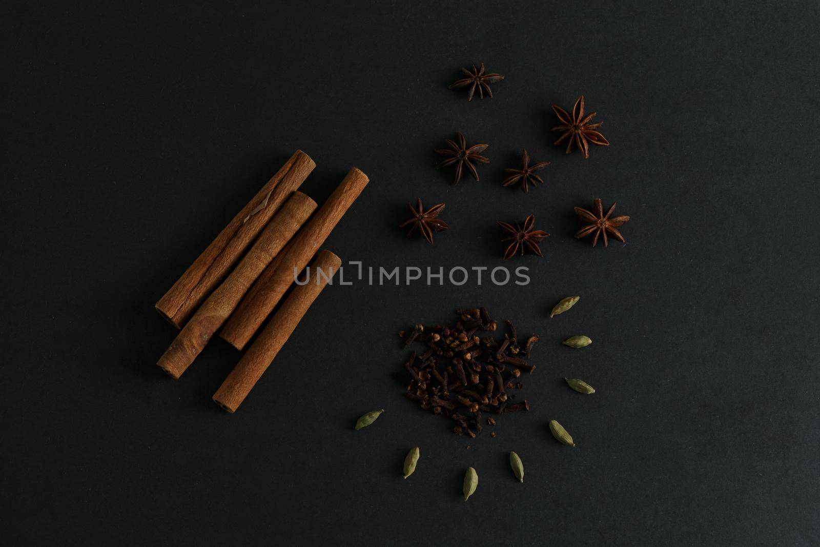 Cinnamon sticks, anise stars, clove and cardamon seed on black background flatlay by Senorina_Irina