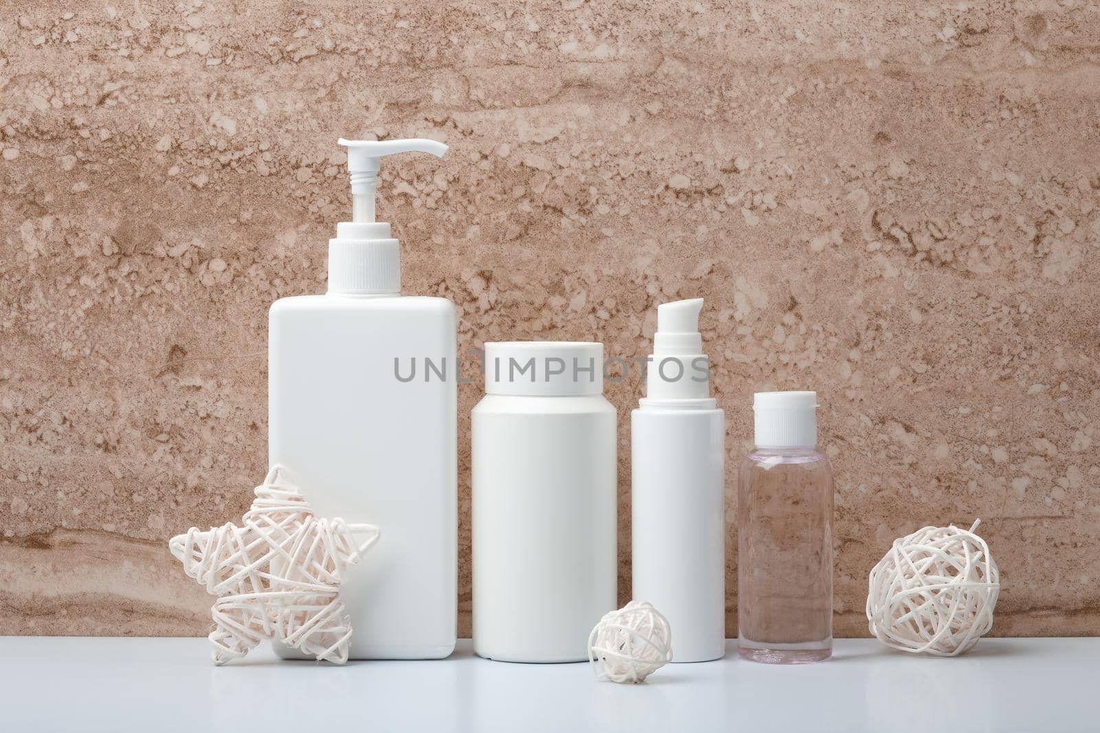 Body cream, scrub, face cream and lotion in white unbranded tubes against beige marble background