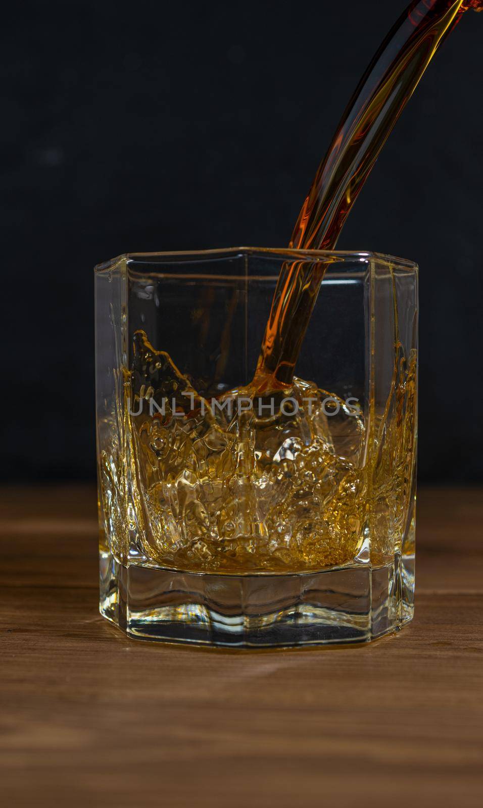 Whiskey drinks on wood with ice cubes and splash by sashokddt