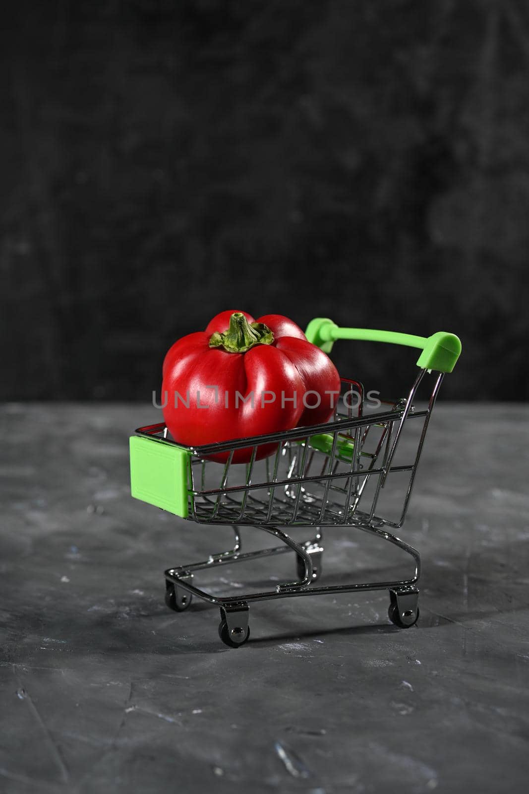 pepper in the tiny supermarket cart on black. The concept of healthy eating. by sashokddt