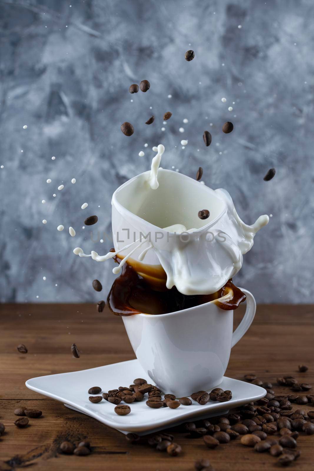 splash and splatter from a piece of sugar in a mug with coffee and mug with milk on a wooden background.