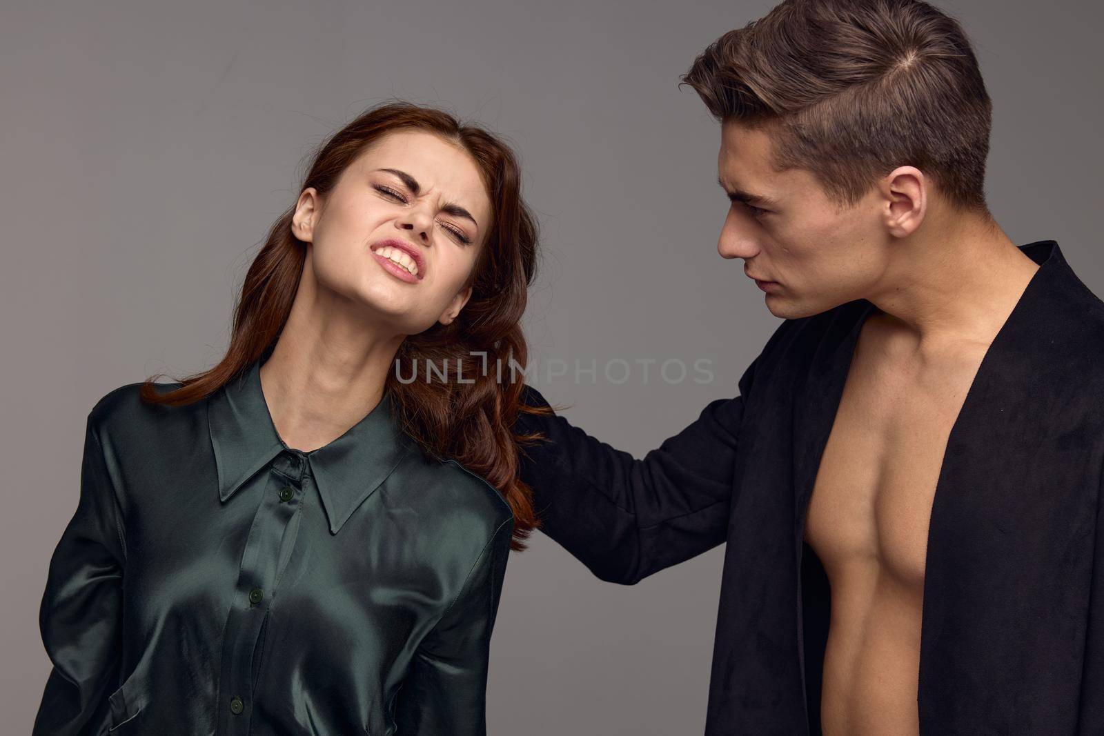 A man pulls the hair of a red-haired woman on a gray background. High quality photo