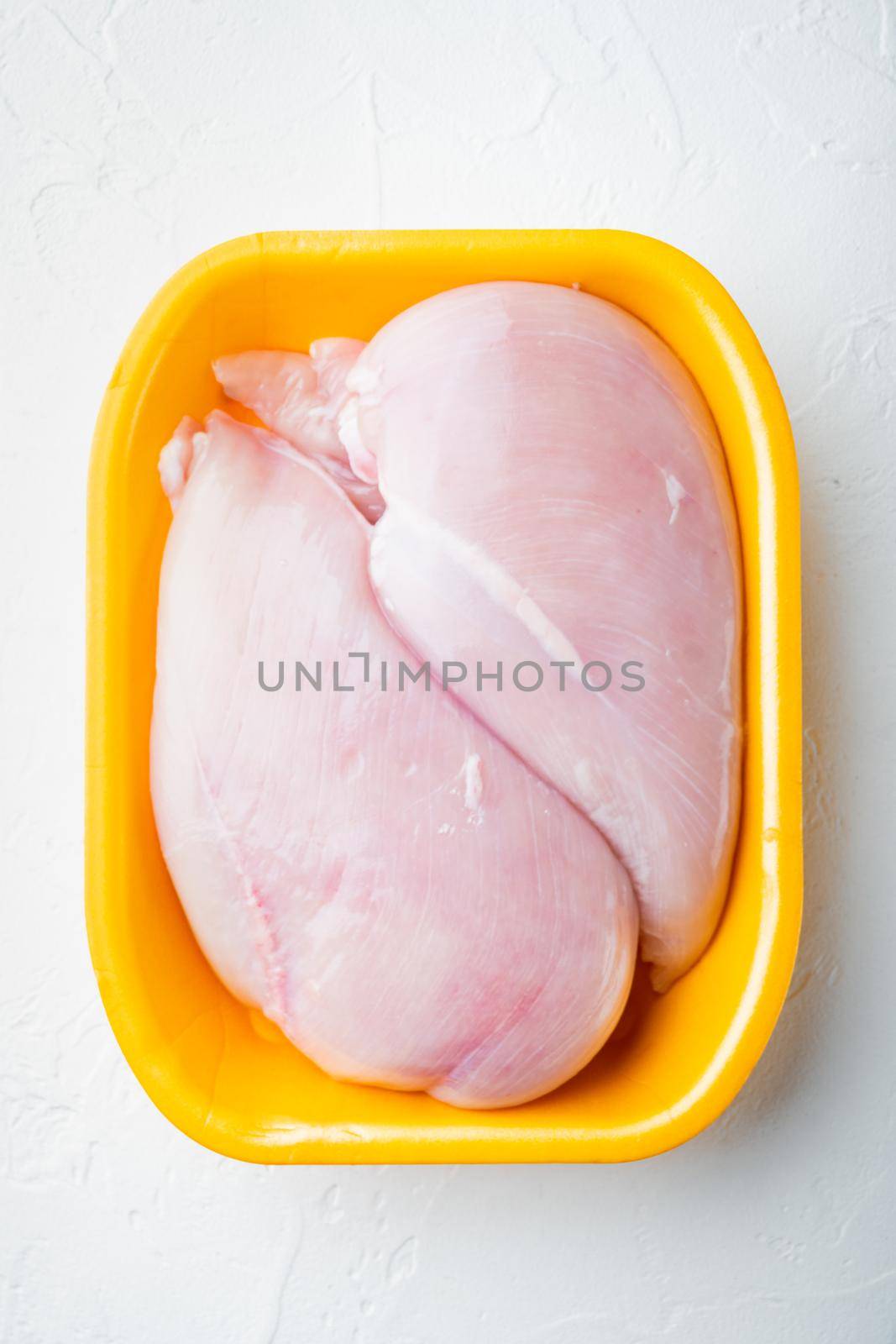 Raw chicken breast fillets in tray, on white background