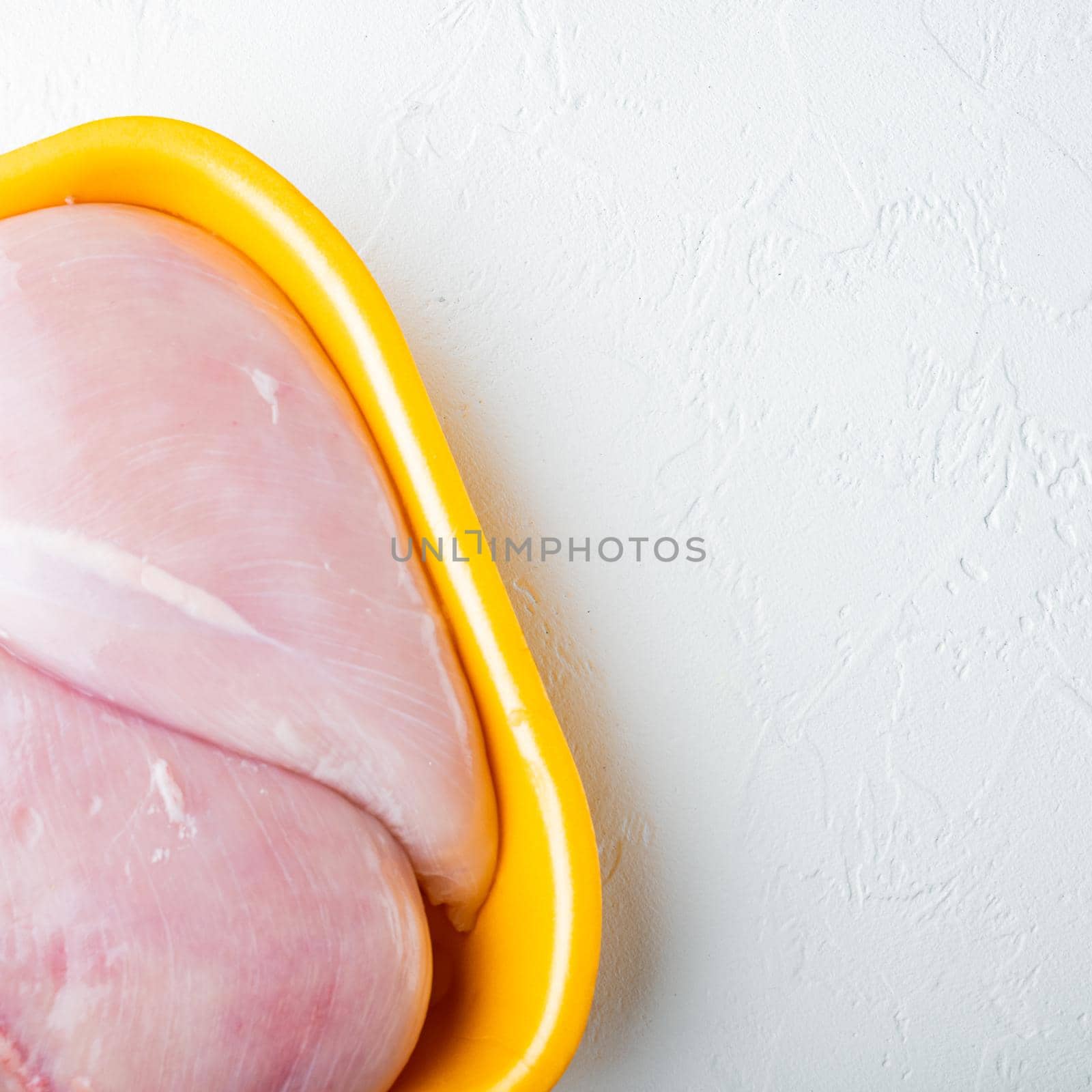 Fresh chicken breast meat in open tray, on white background with copy space for text