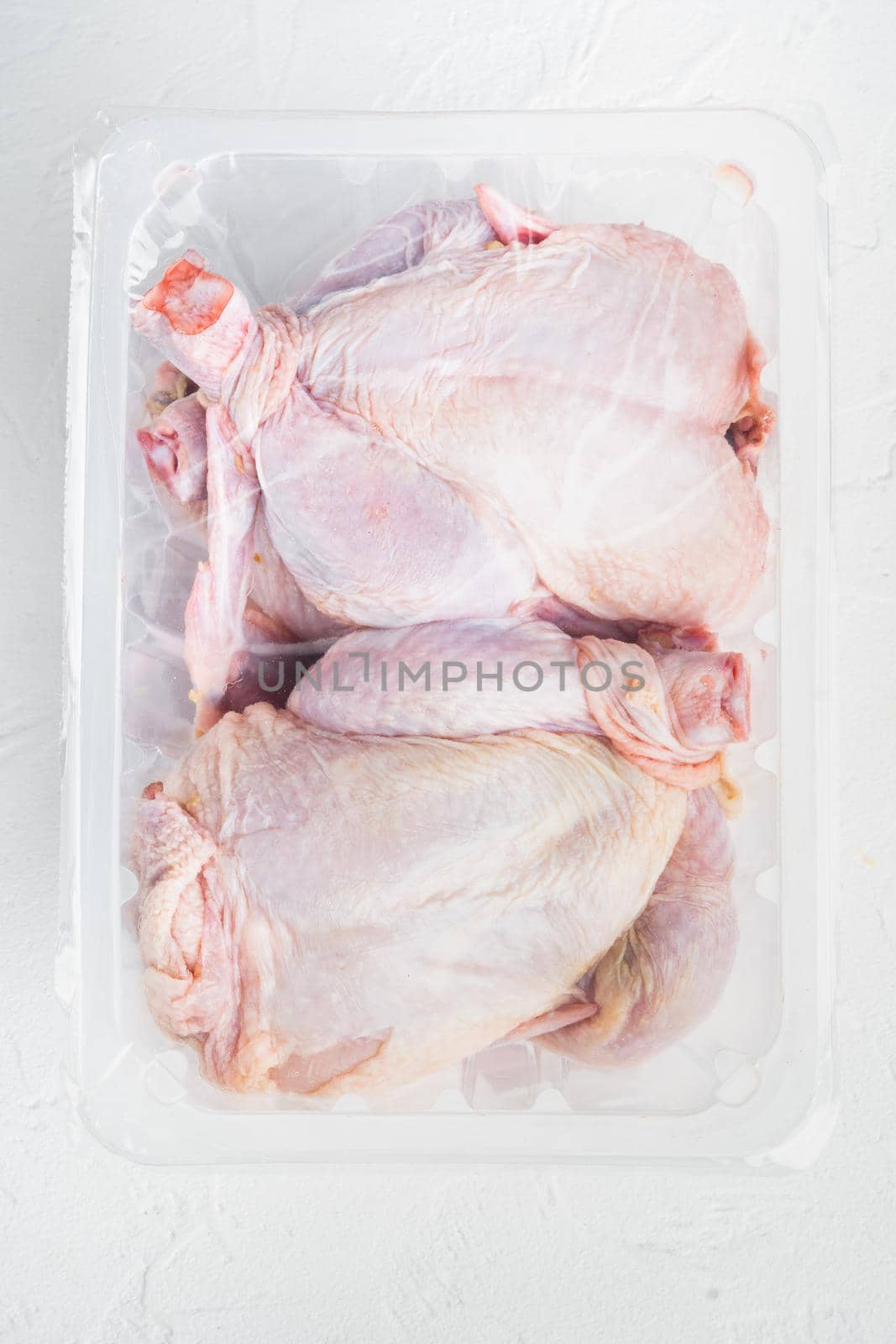 Plastic container with raw chicken set, on white background, top view