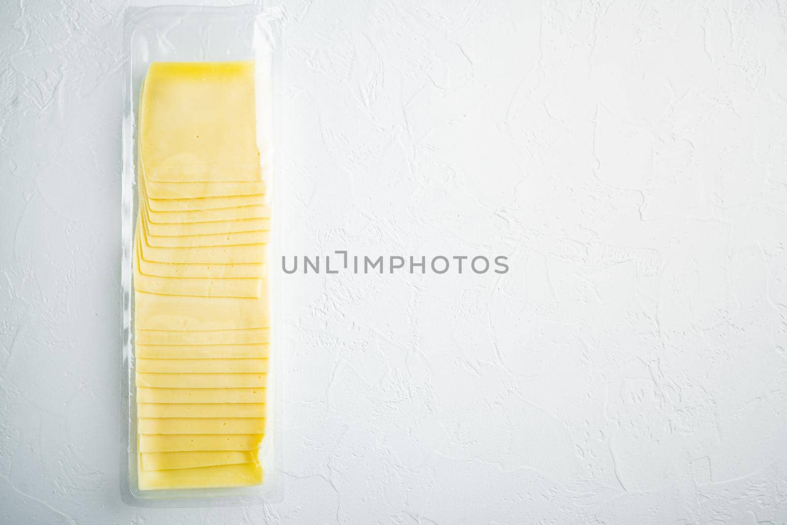 Slices of yellow cheese, sealed pack, on white background with copy space for text
