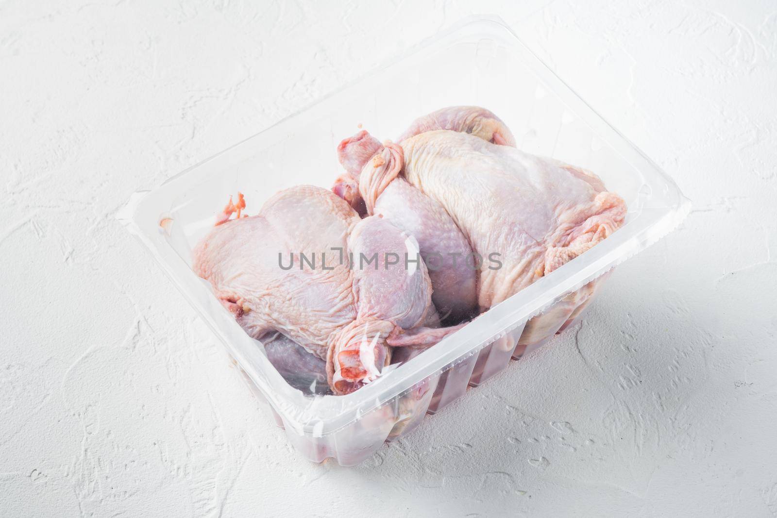 Raw chicken set in plastic vacuum tray, on white background