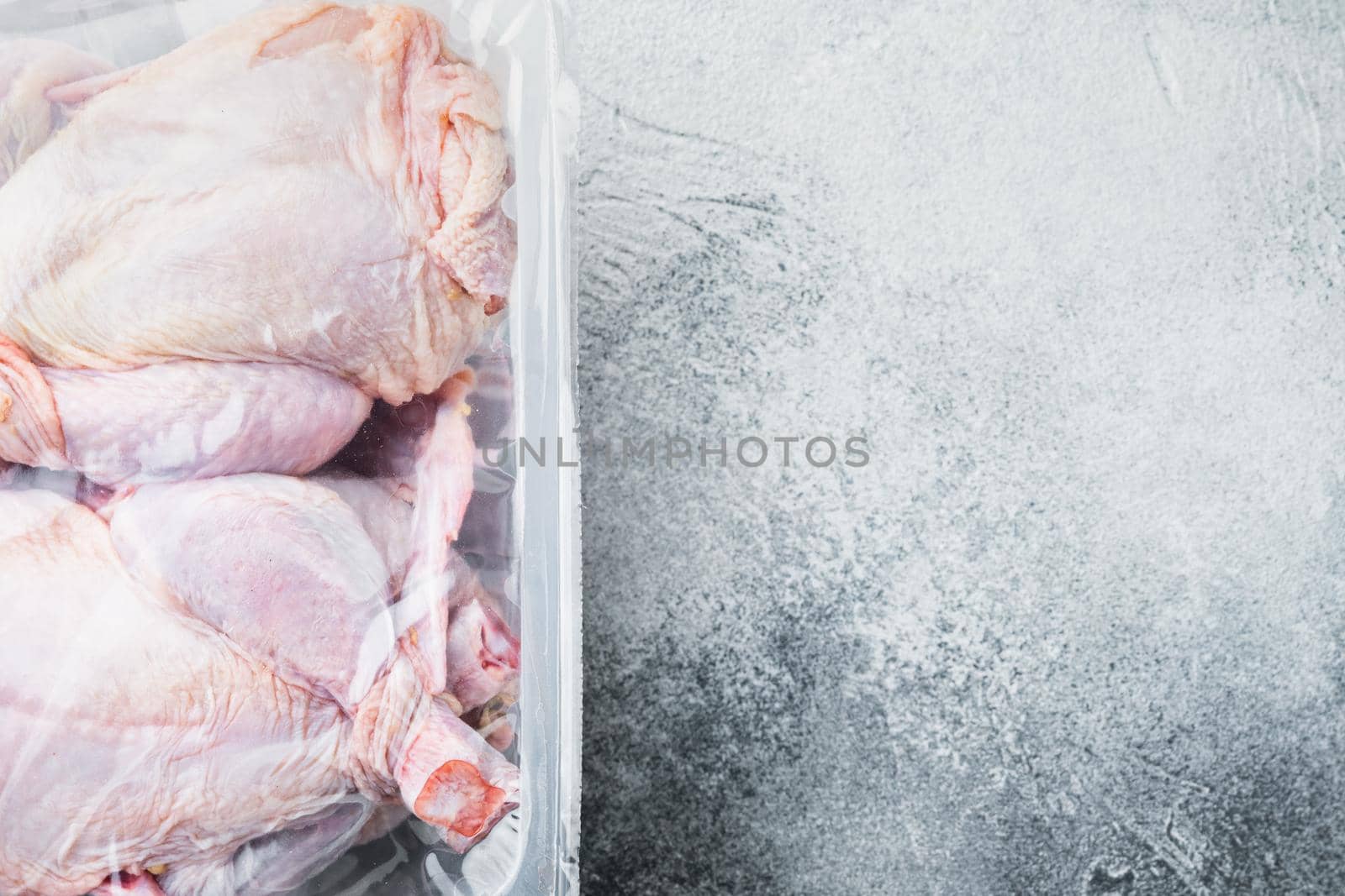 Plastic container with raw chicken set, on gray background, top view with copy space for text