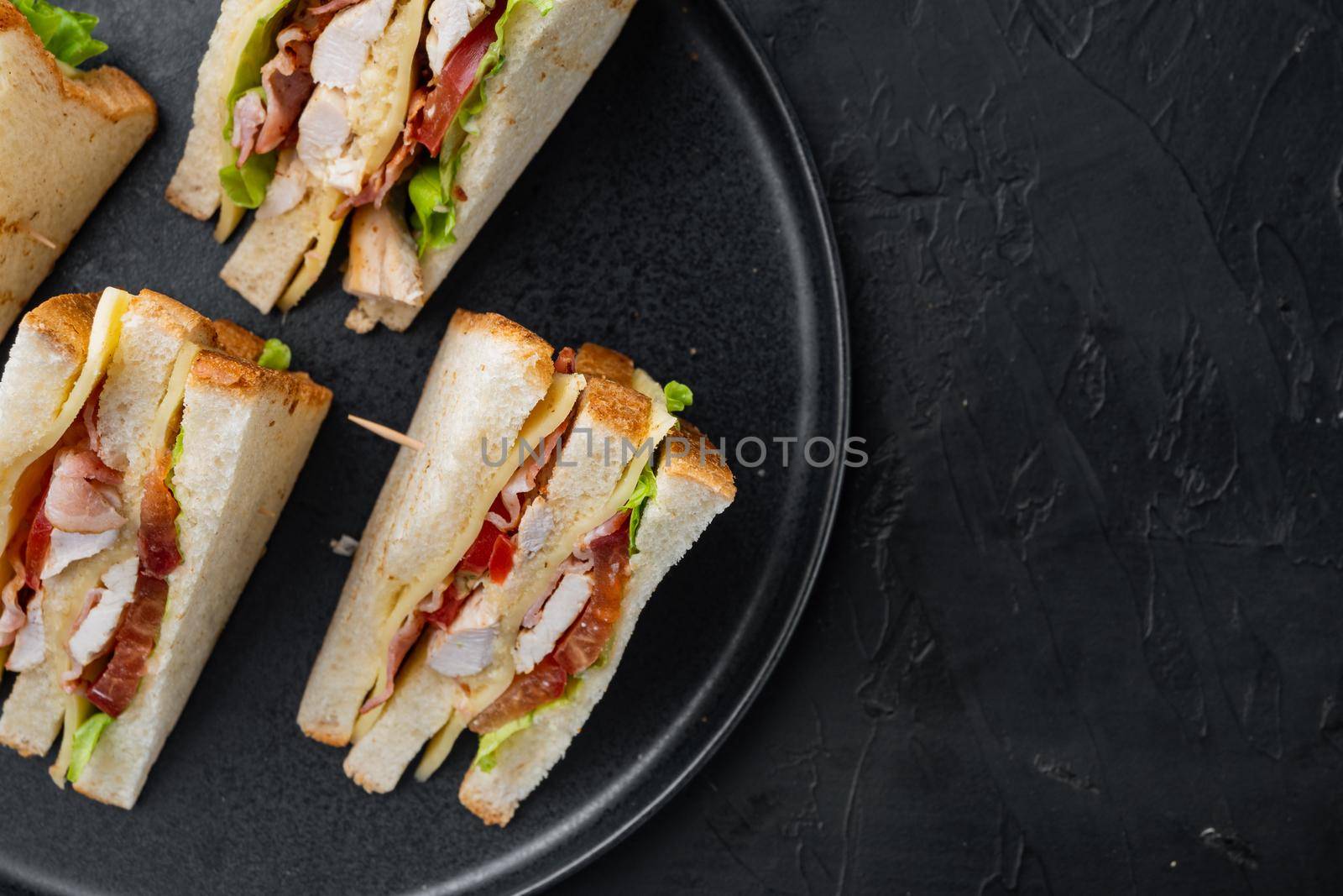Homemade chicken sandwich halves, on black background, top view with copy space for text