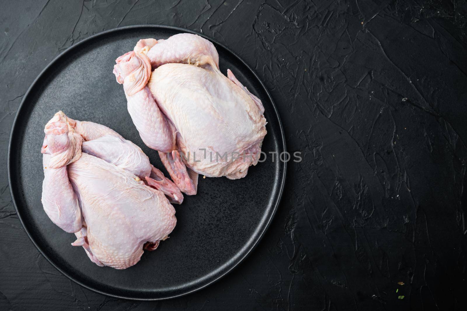 Organic whole fresh poussins, on black background, top view with copy space for text
