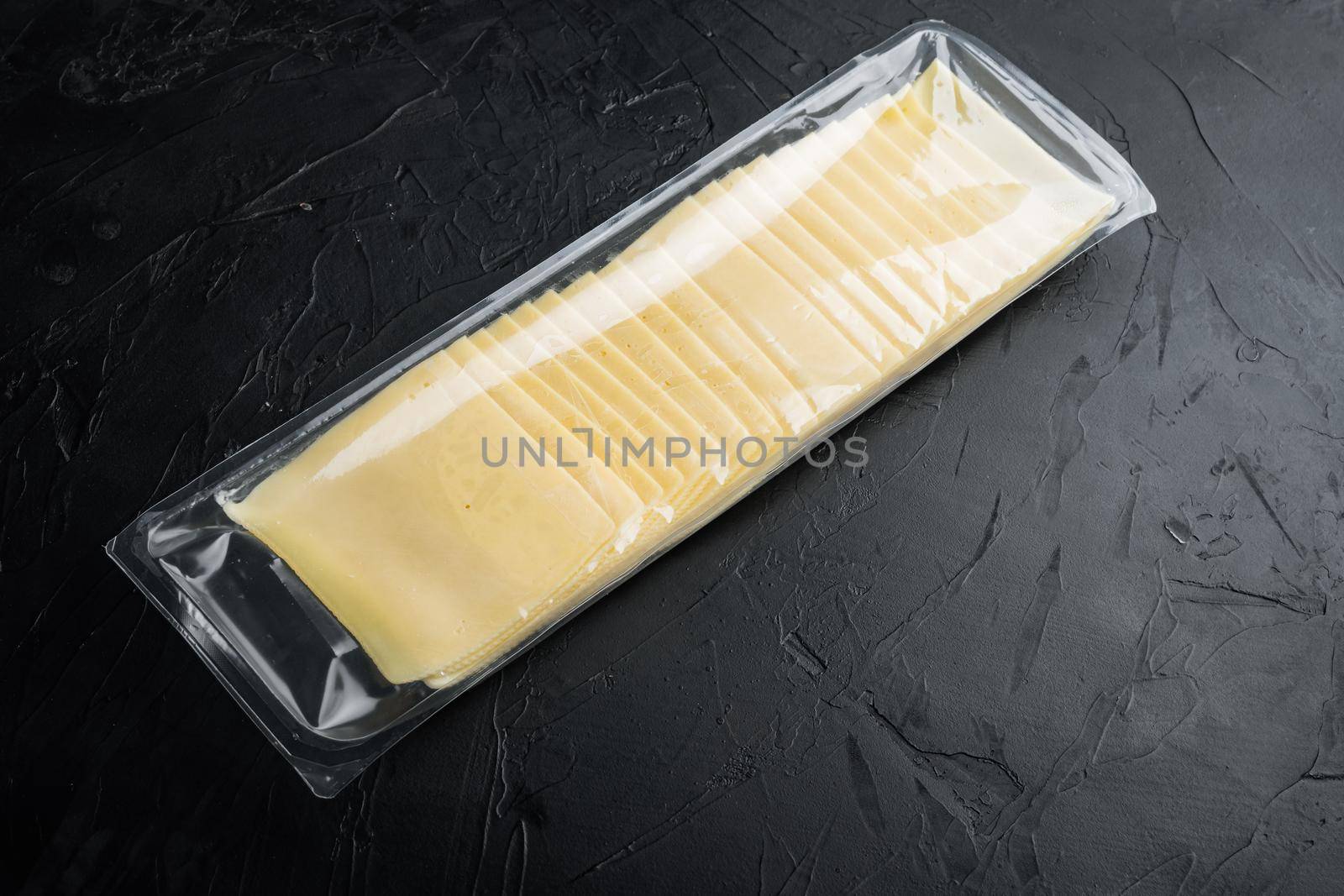 Cheddar cheese in vacuum pack, on black background with copy space for text
