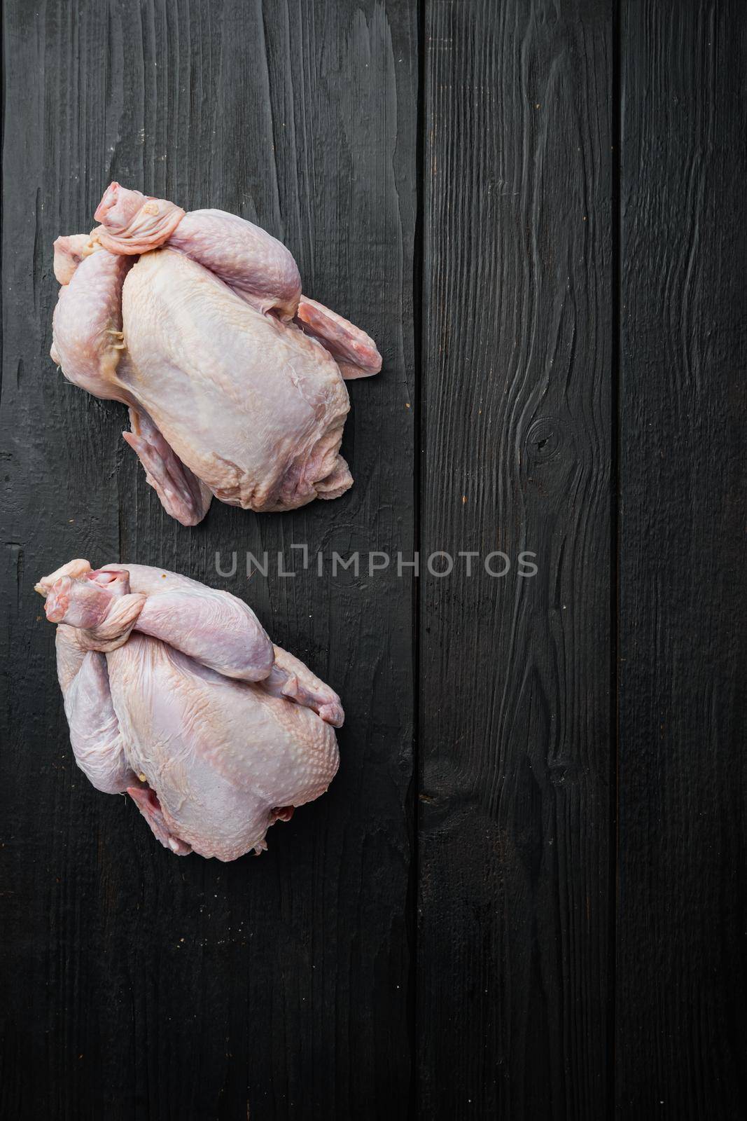 Organic whole fresh poussins, on black wooden table, top view with copy space for text