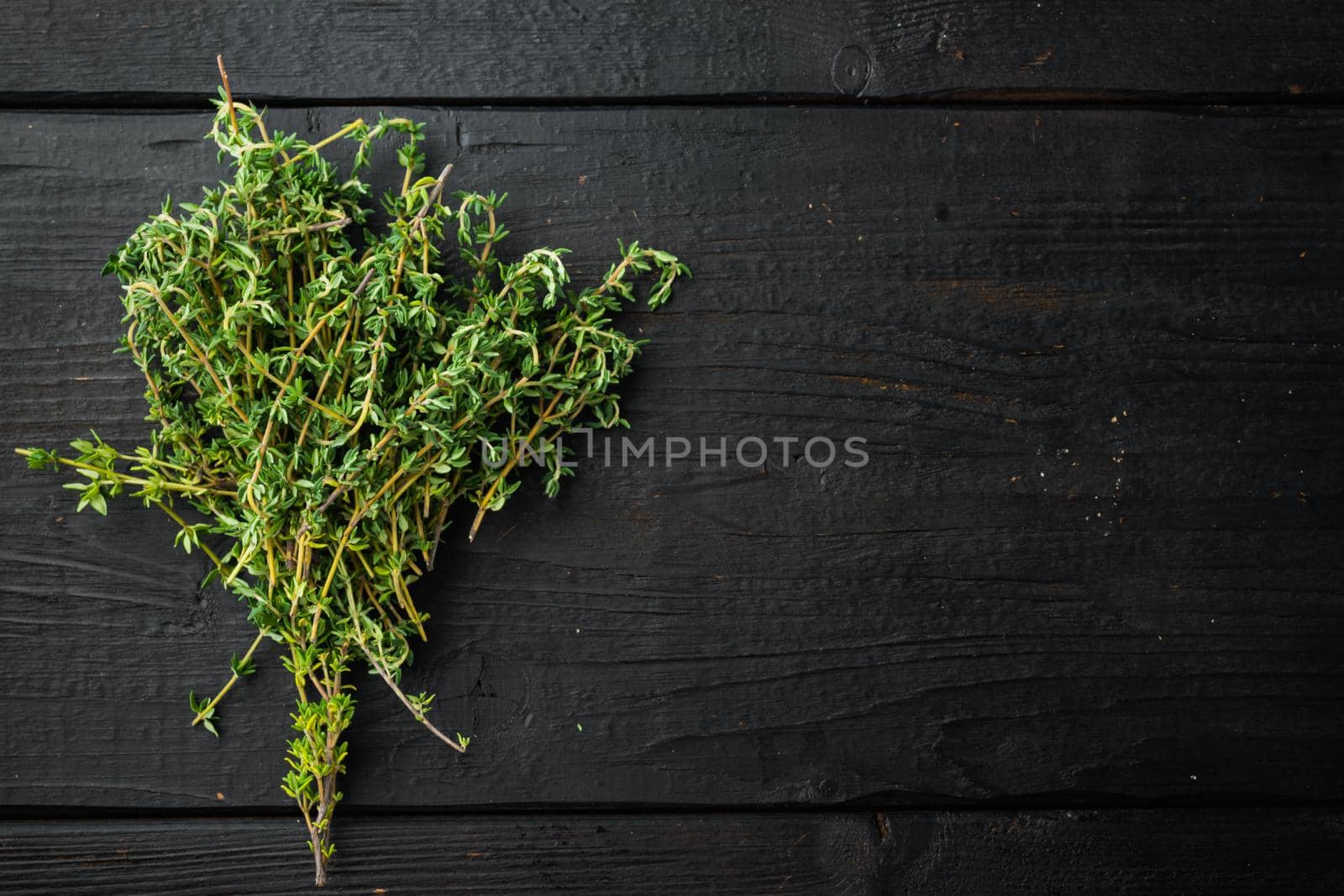 Thyme green fresh bunch, on black wooden background, top view with copy space for text