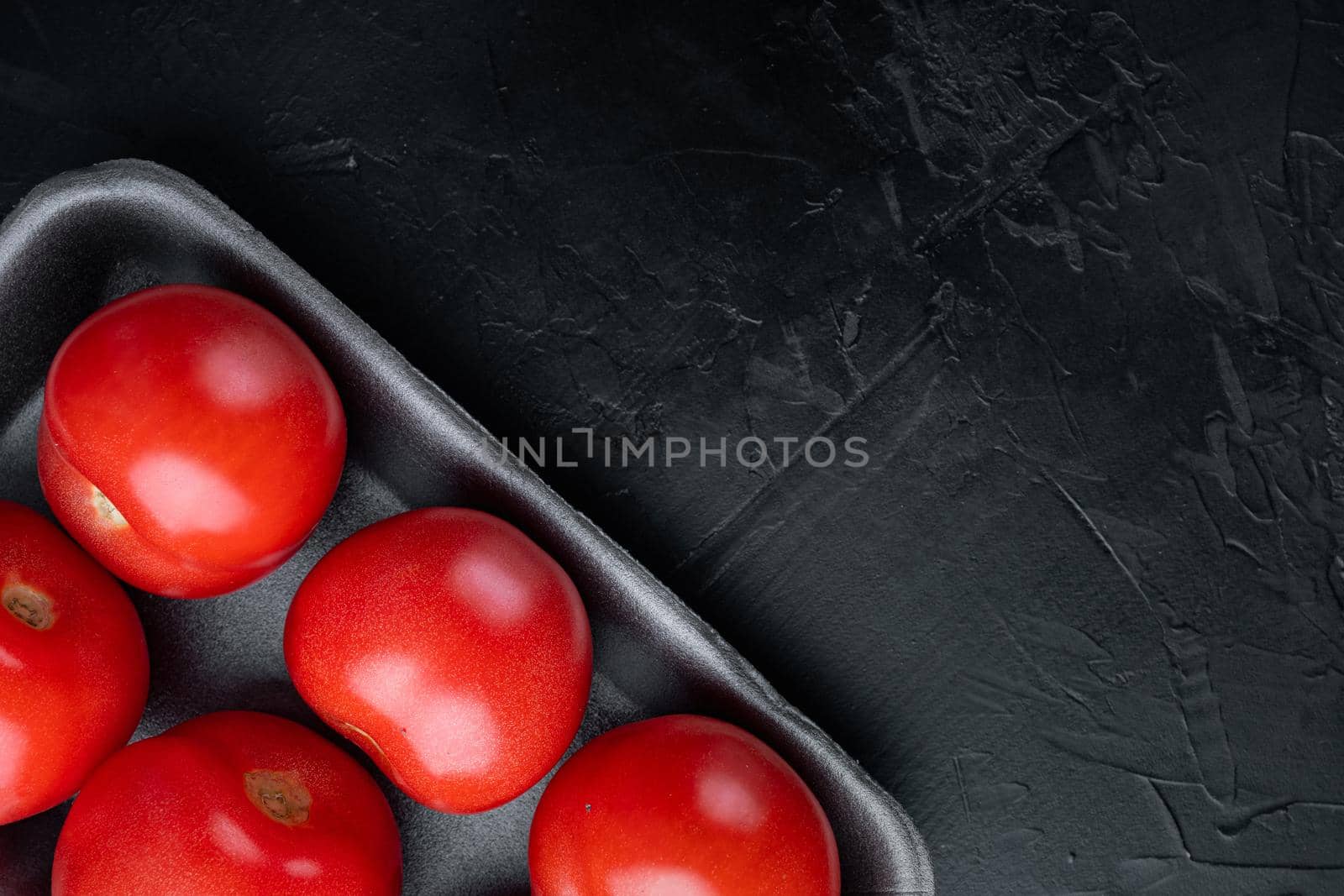 Red ripe tomatoes, on black background with copy space for text