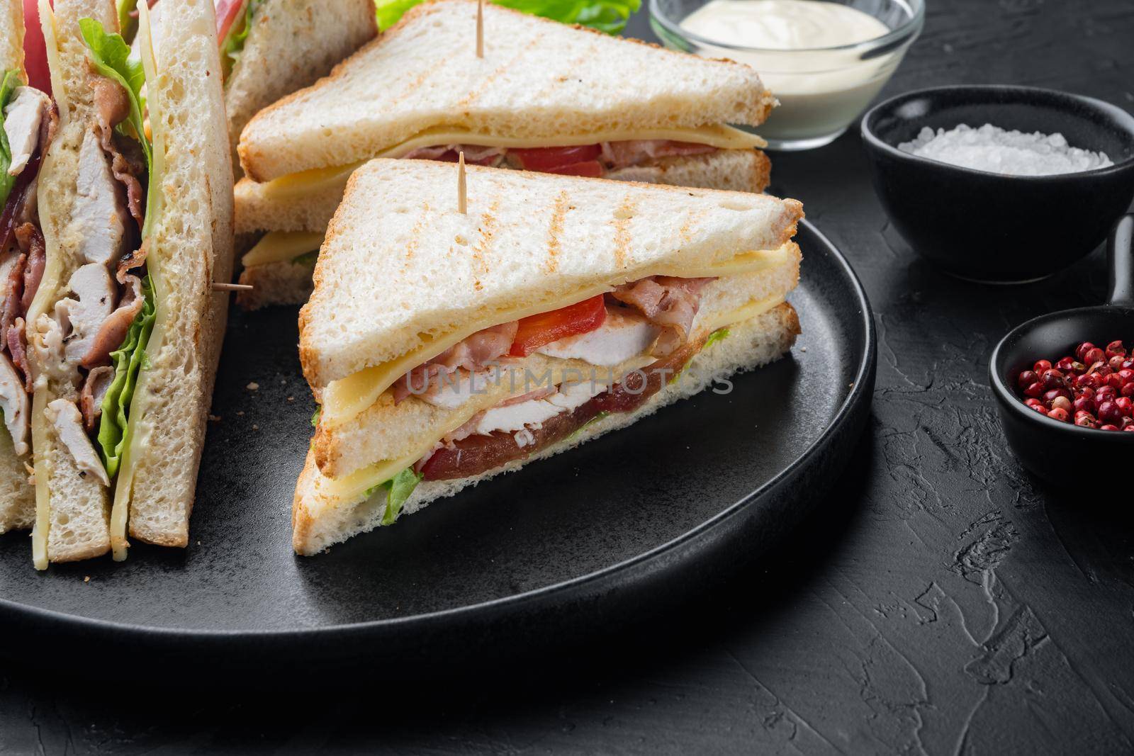 Homemade turkey club sandwich, on black background