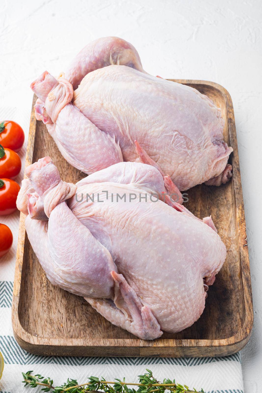 Raw organic uncooked whole chicken meat with herbs and ingredients, on white background