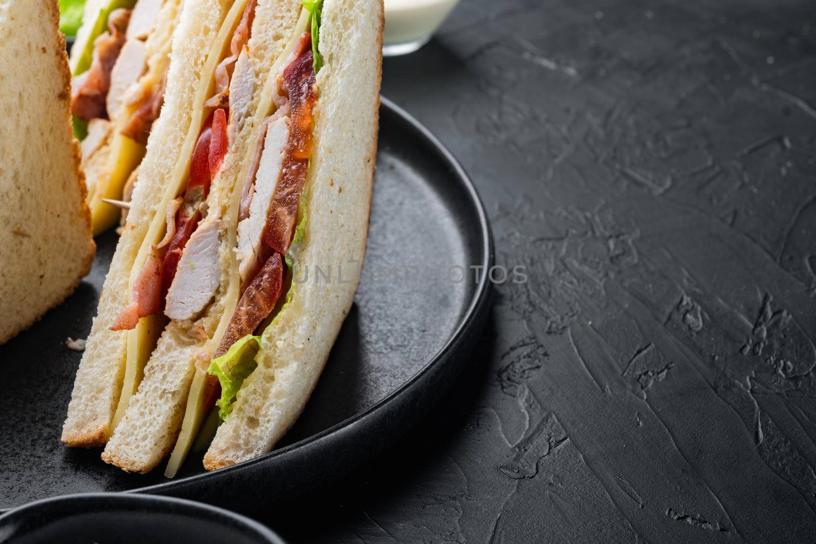Club sandwich panini with ham, fresh tomato, cheese, on black background with copy space for text