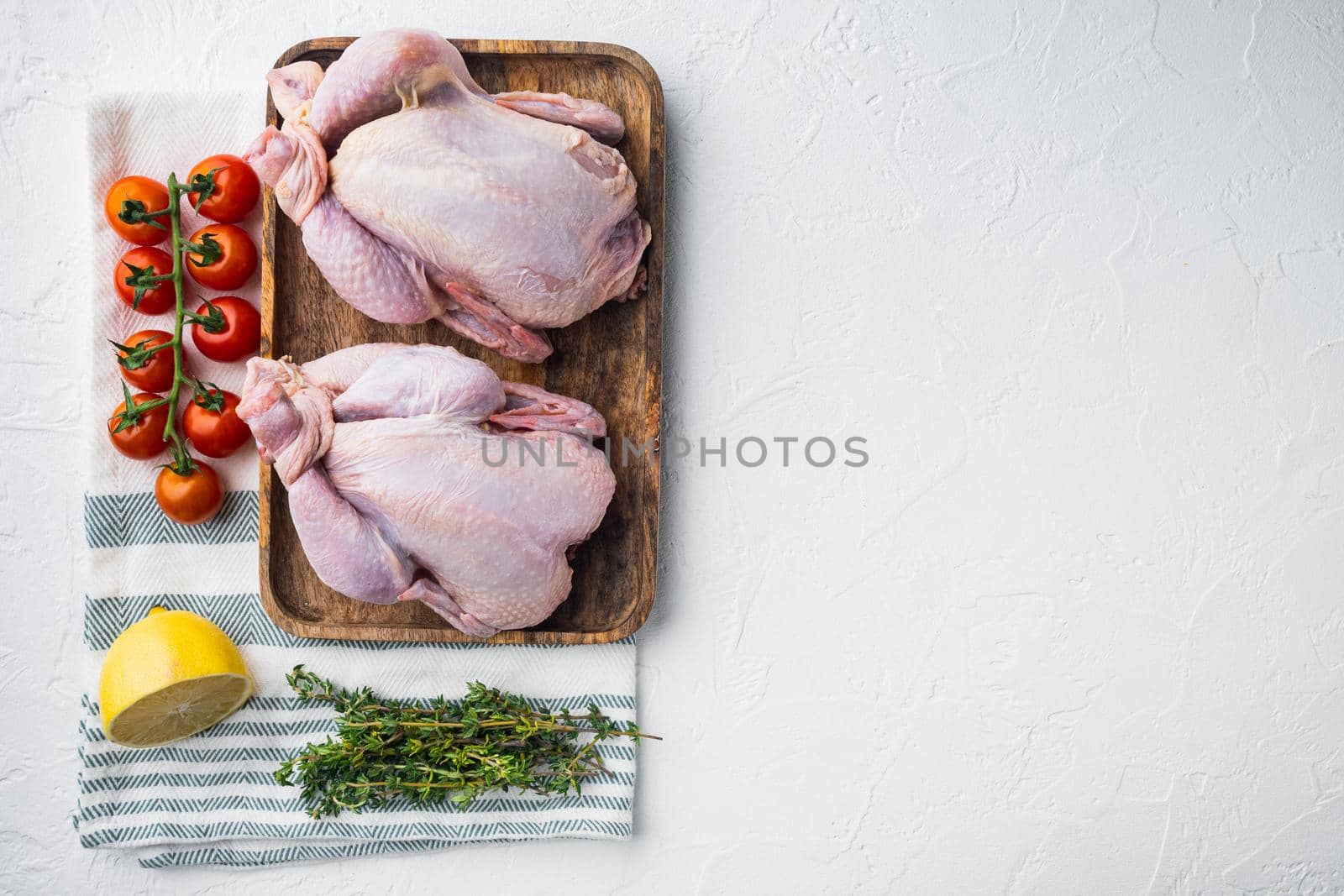 Raw coquelet chickens meat with herbs and ingredients, on white background, top view with copy space for text