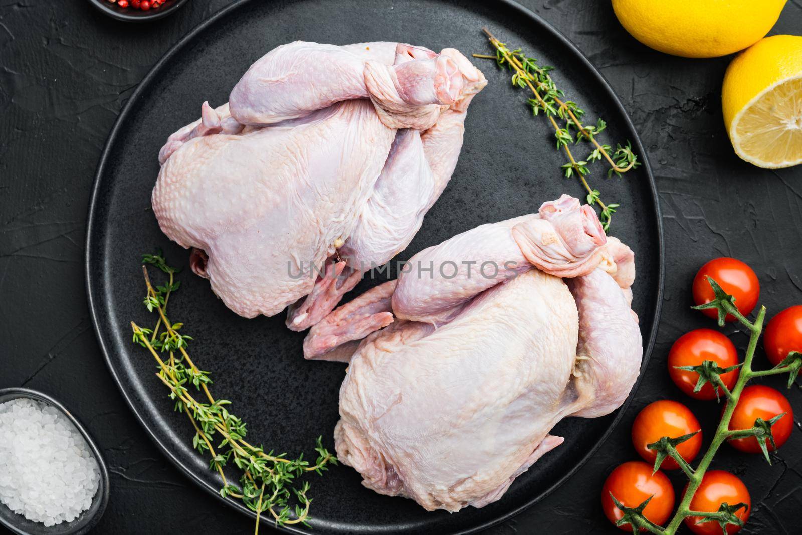 Organic whole fresh poussins with herbs spices, on black background, top view