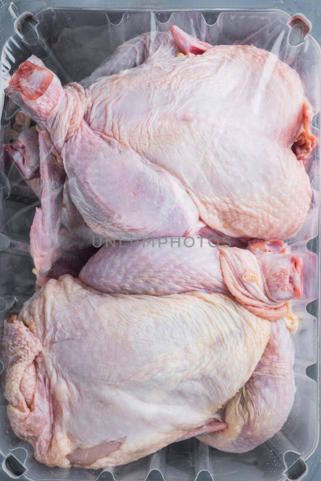 Plastic container with raw chicken set, on black wooden table, top view