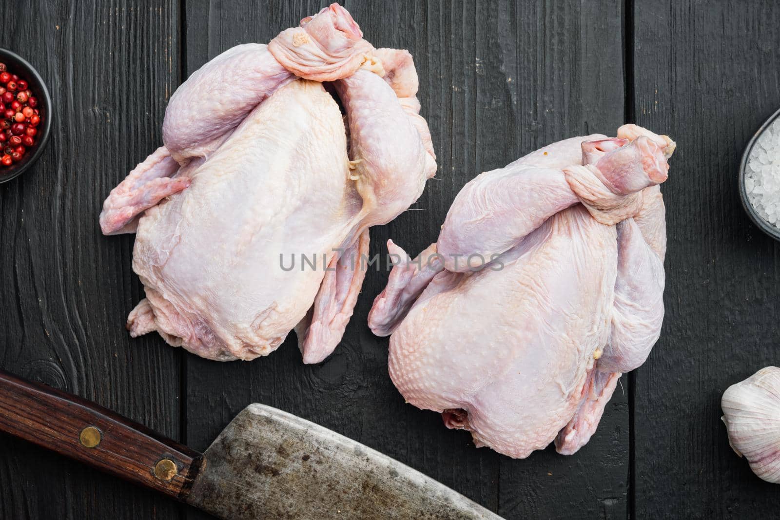 Fresh raw chicken meat with herbs spices, on black wooden table, top view