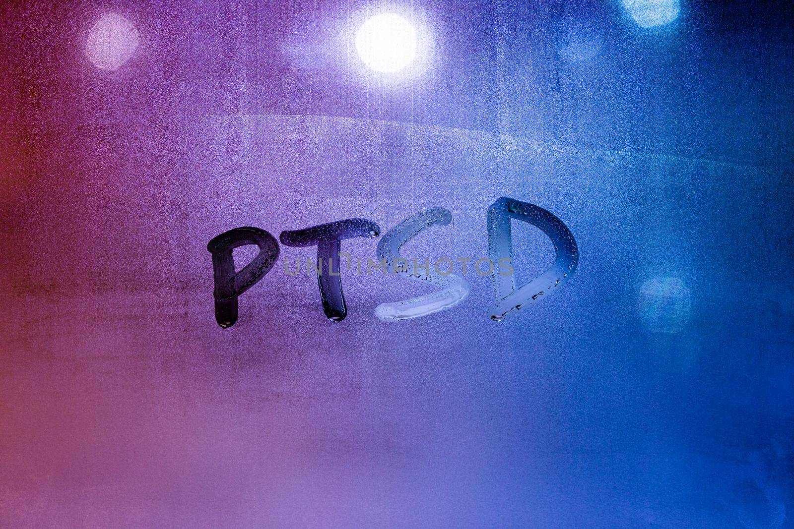 abbreviation ptsd - post traumatic stress disorder - handwritten on night wet window glass, close-up with selective focus