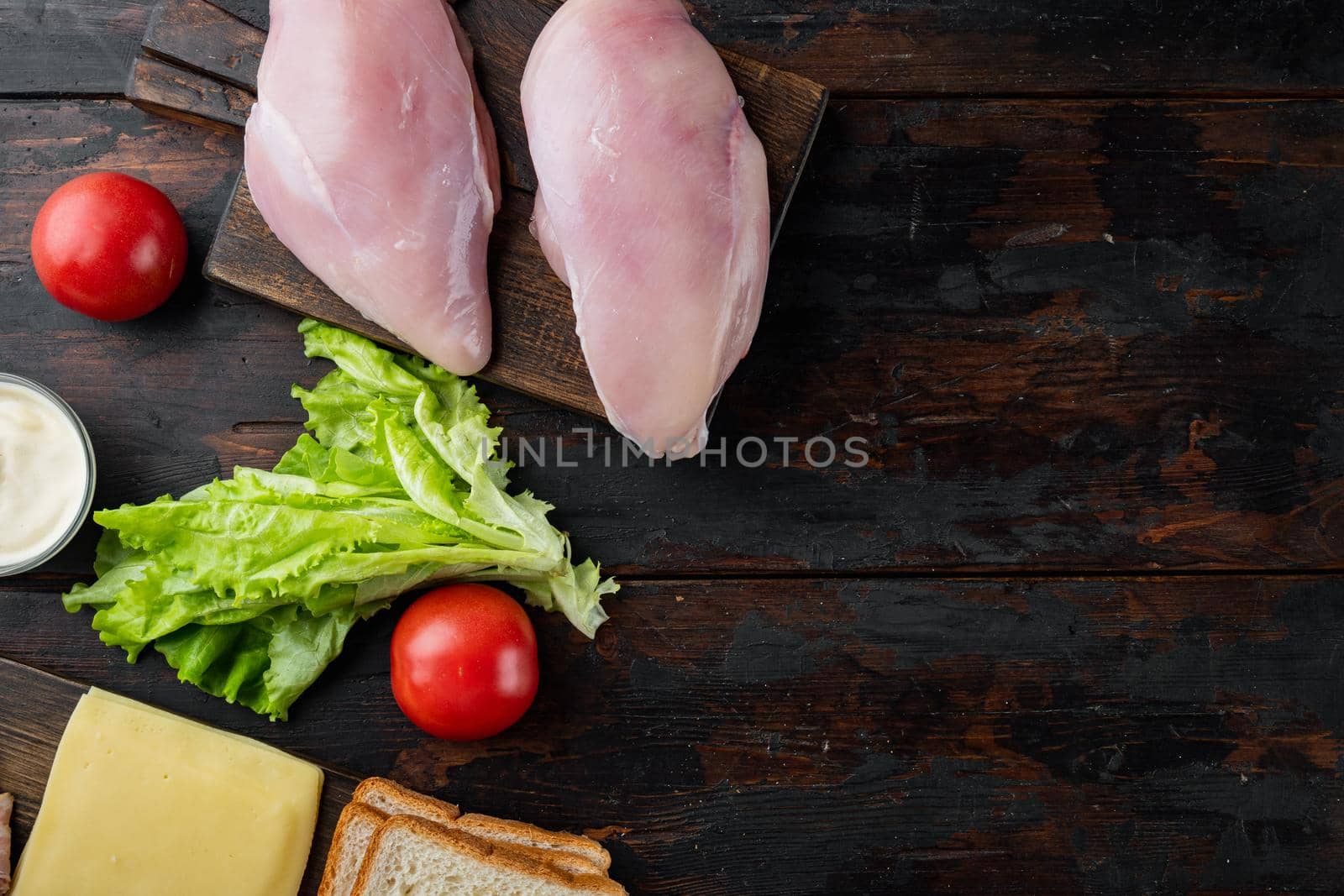 Ingredients for sandwich, bacon, cheese, tomato, chicken meat, lettuce, sauce, on dark wooden background, top view with copy space for text