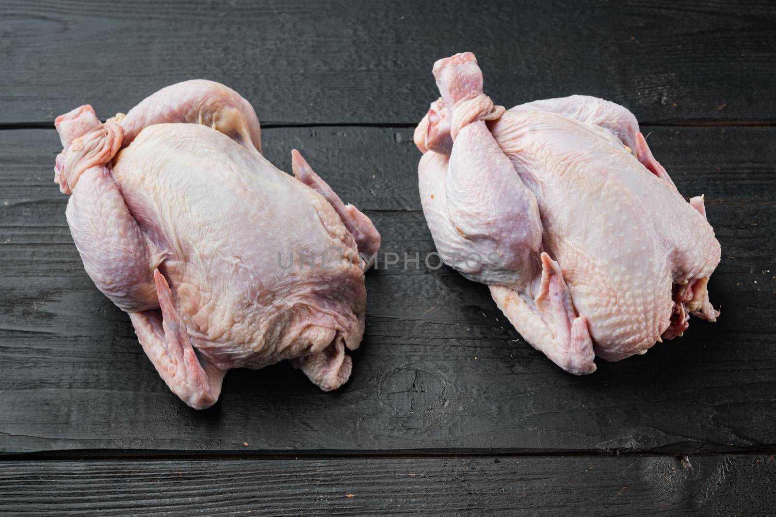 Raw coquelet chickens meat, on black wooden background