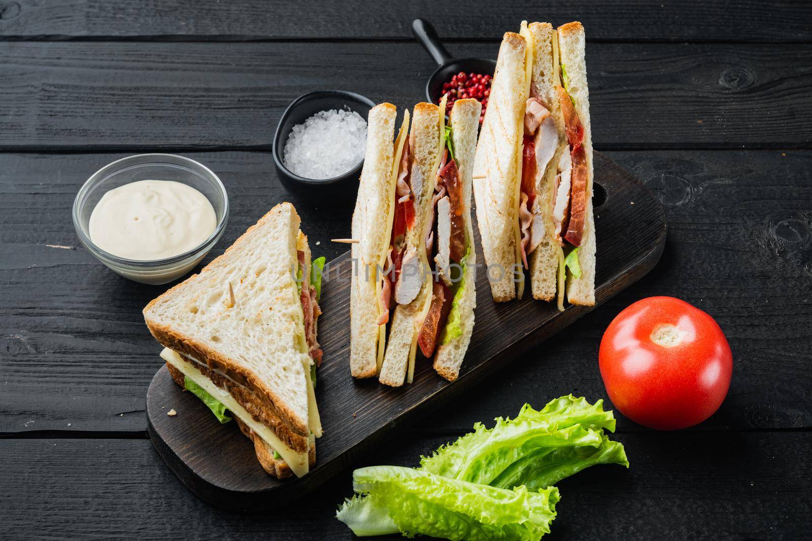 Classic club sandwich with meat, on black wooden table
