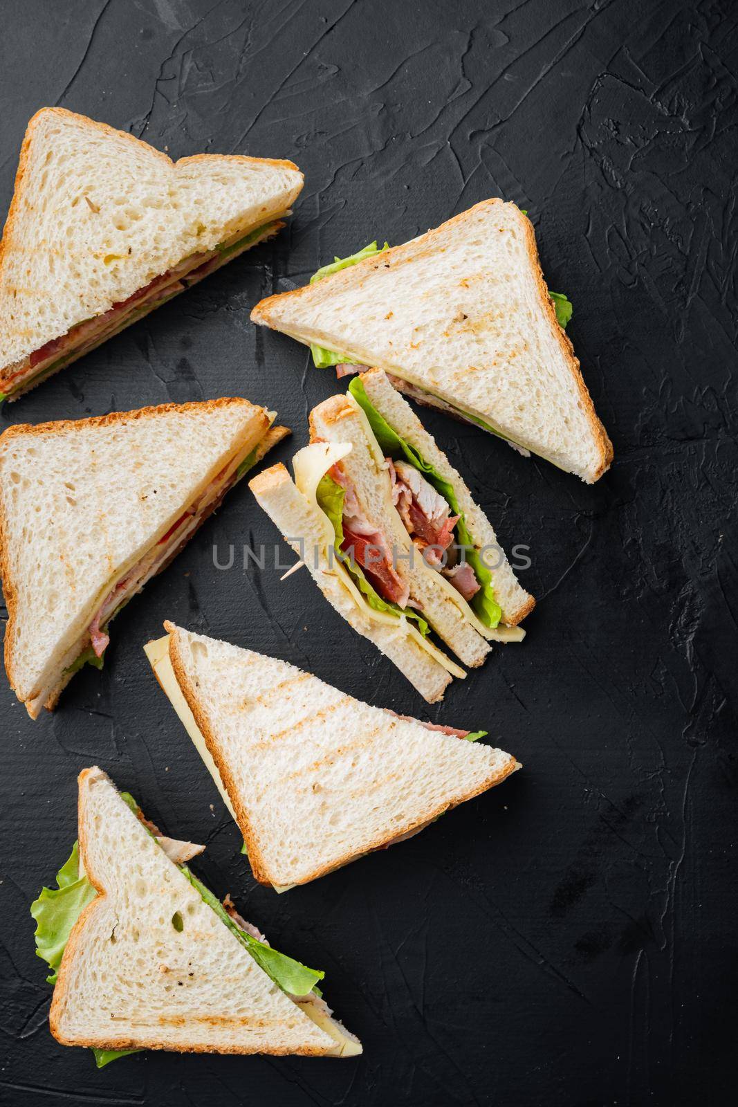 Club sandwich panini with ham, fresh tomato, cheese, on black background, top view