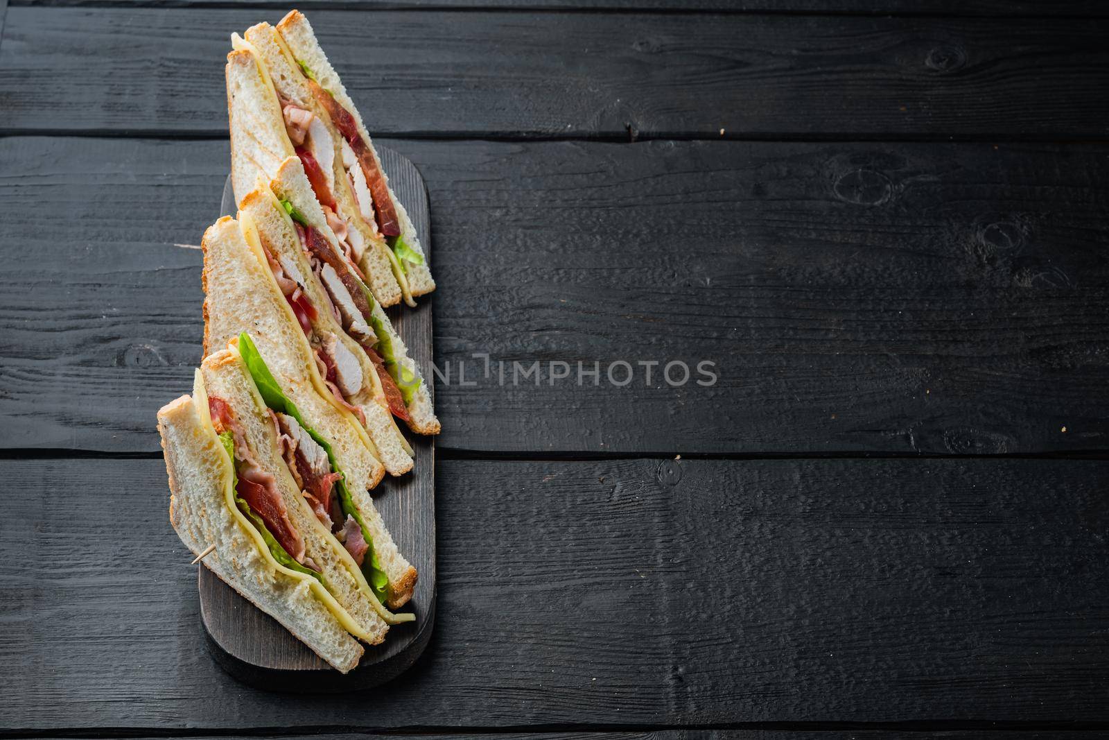 Homemade chicken sandwich halves, on black wooden table with copy space for text