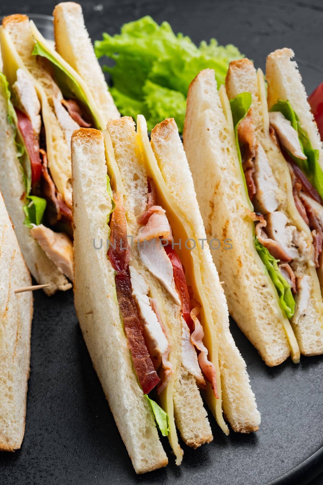 Sandwich bread tomato lettuce and yellow cheese, on black background