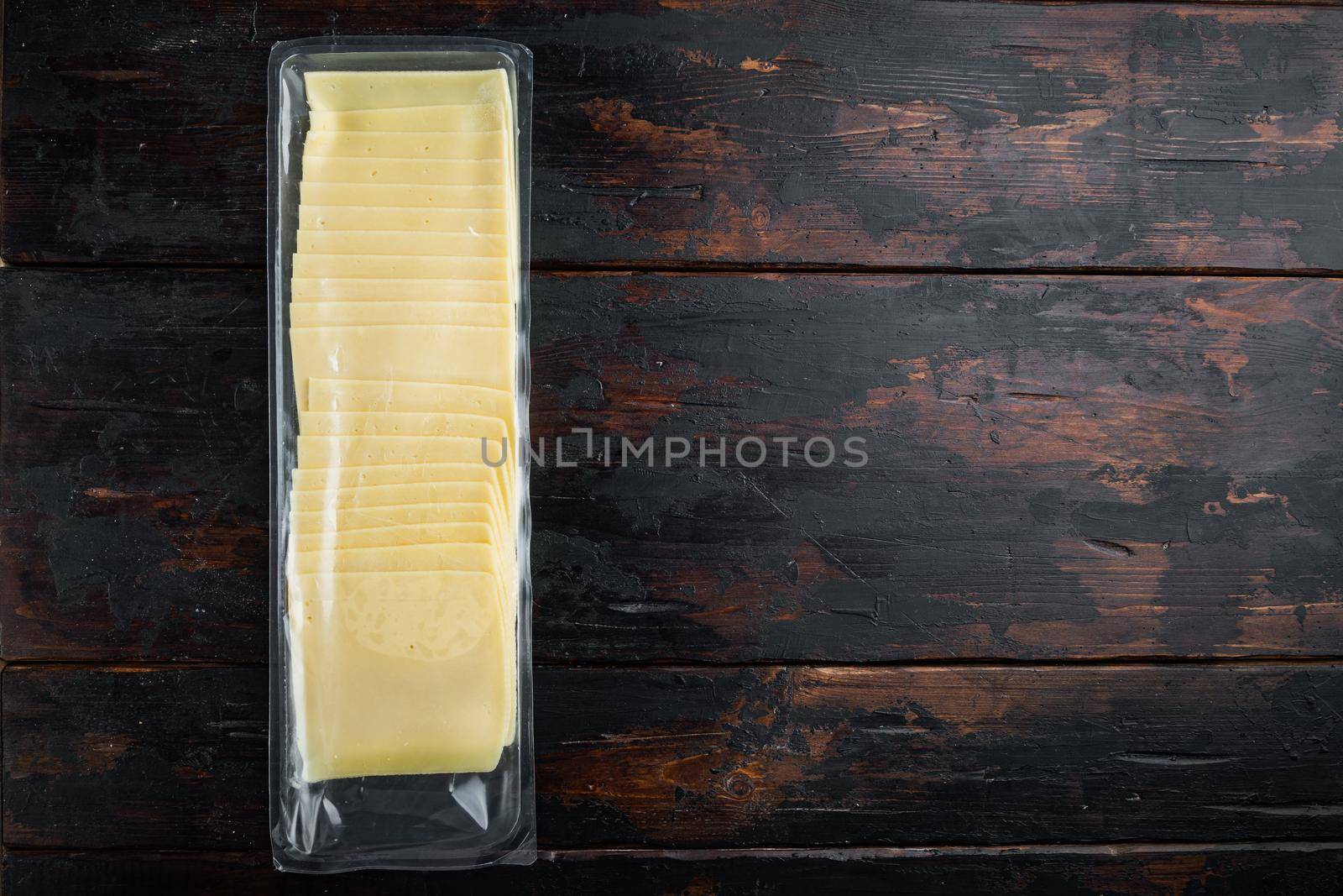 Cheddar cheese in vacuum pack, on dark wooden background with copy space for text