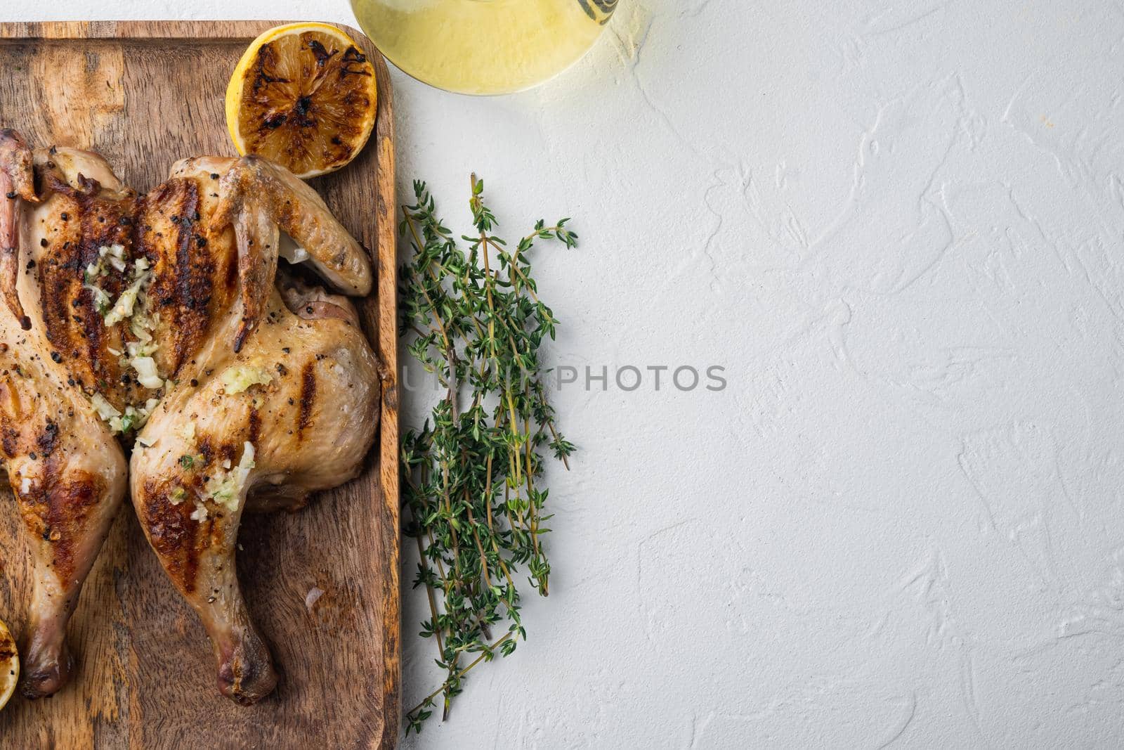 Roasted whole poussins, on white background, top view with copy space for text