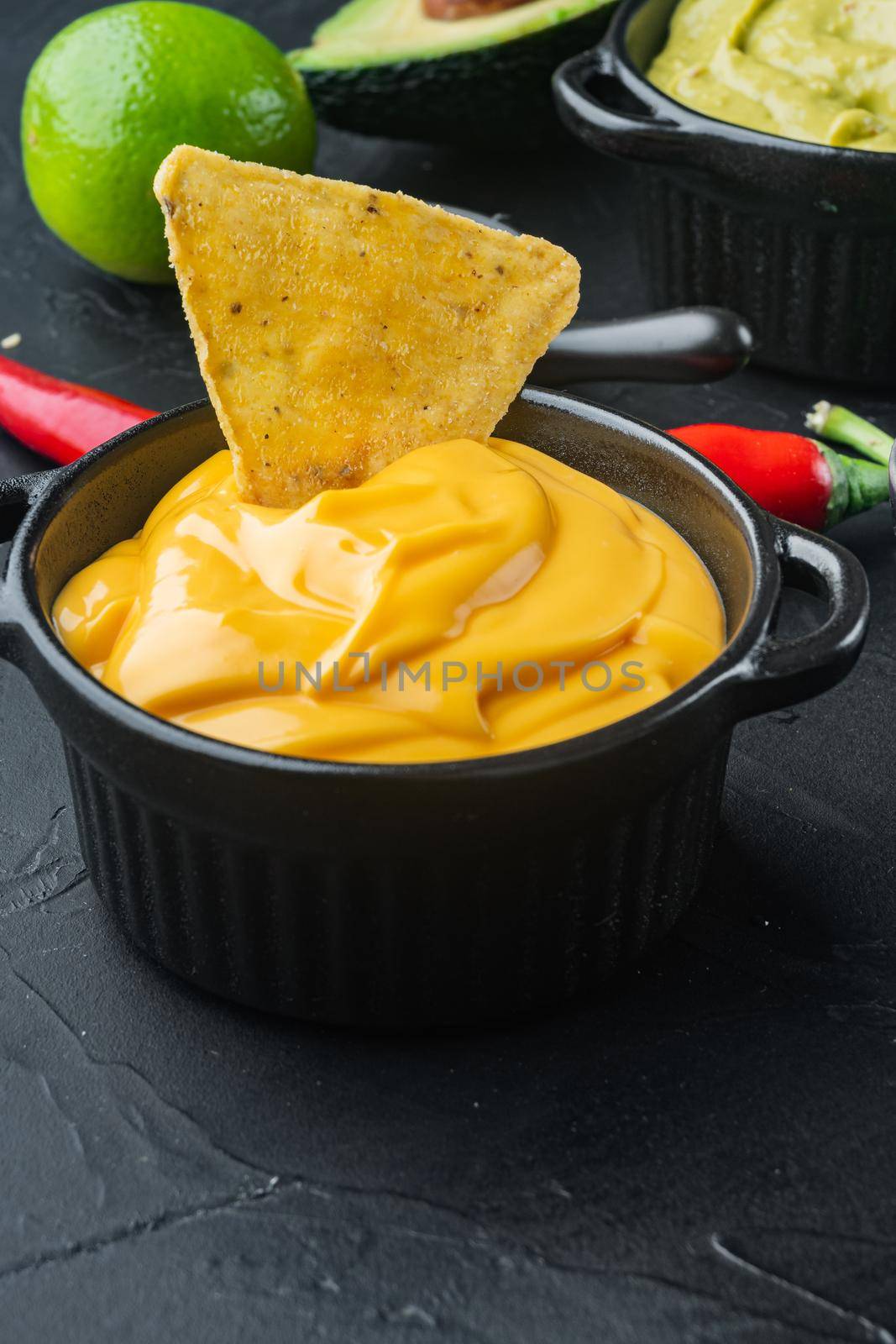 Creamy cheddar sauce with chia seeds in bowl, on black background