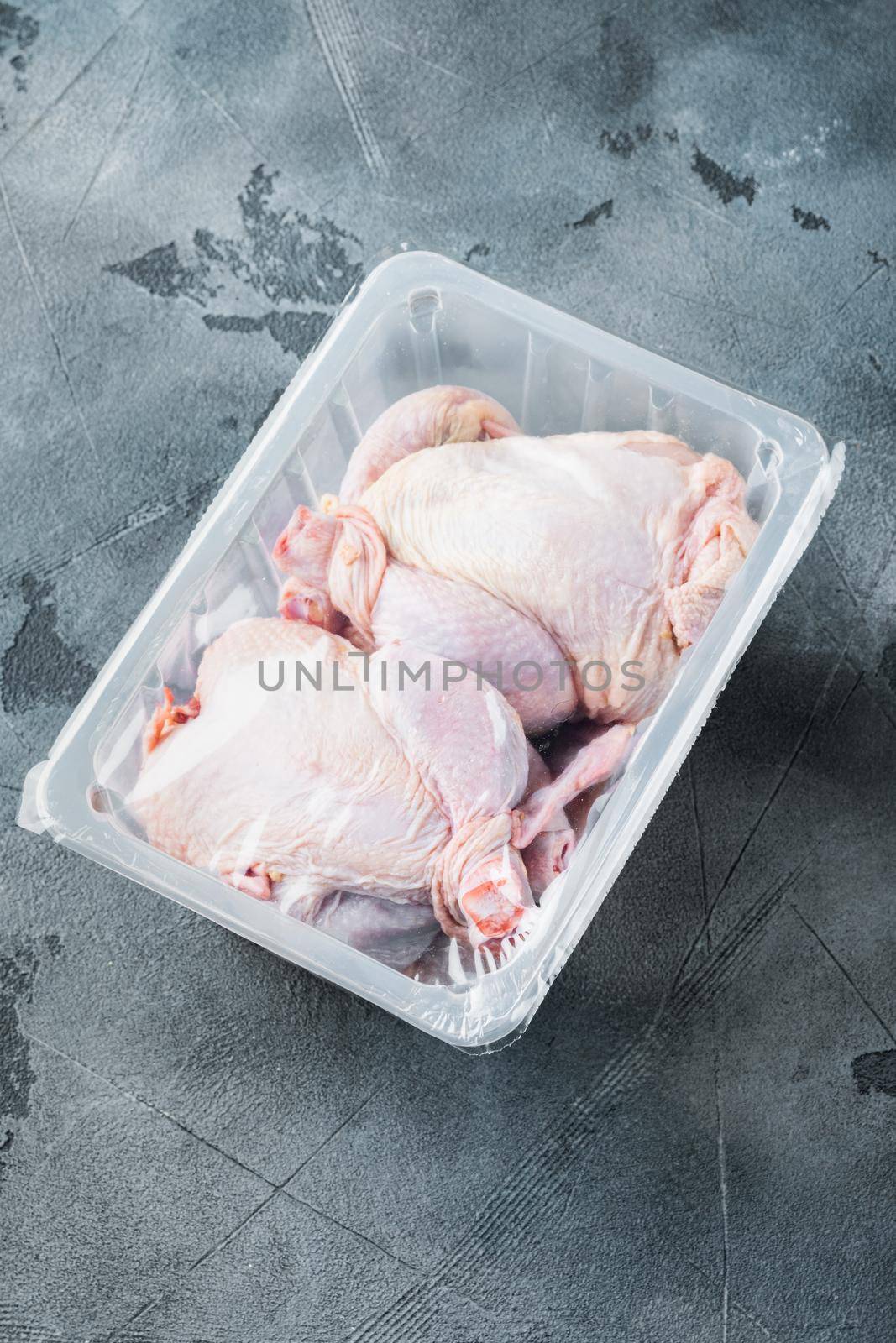 Raw chicken in plastic sealed plastic box, on gray background