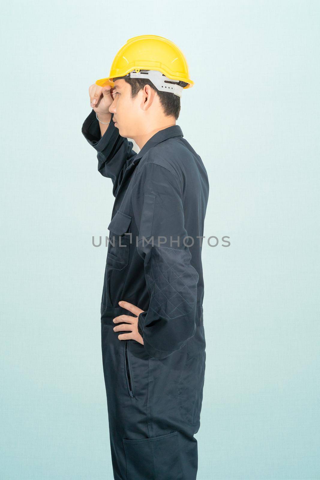 Young man in coveralls helmet hardhat isolated on blue background