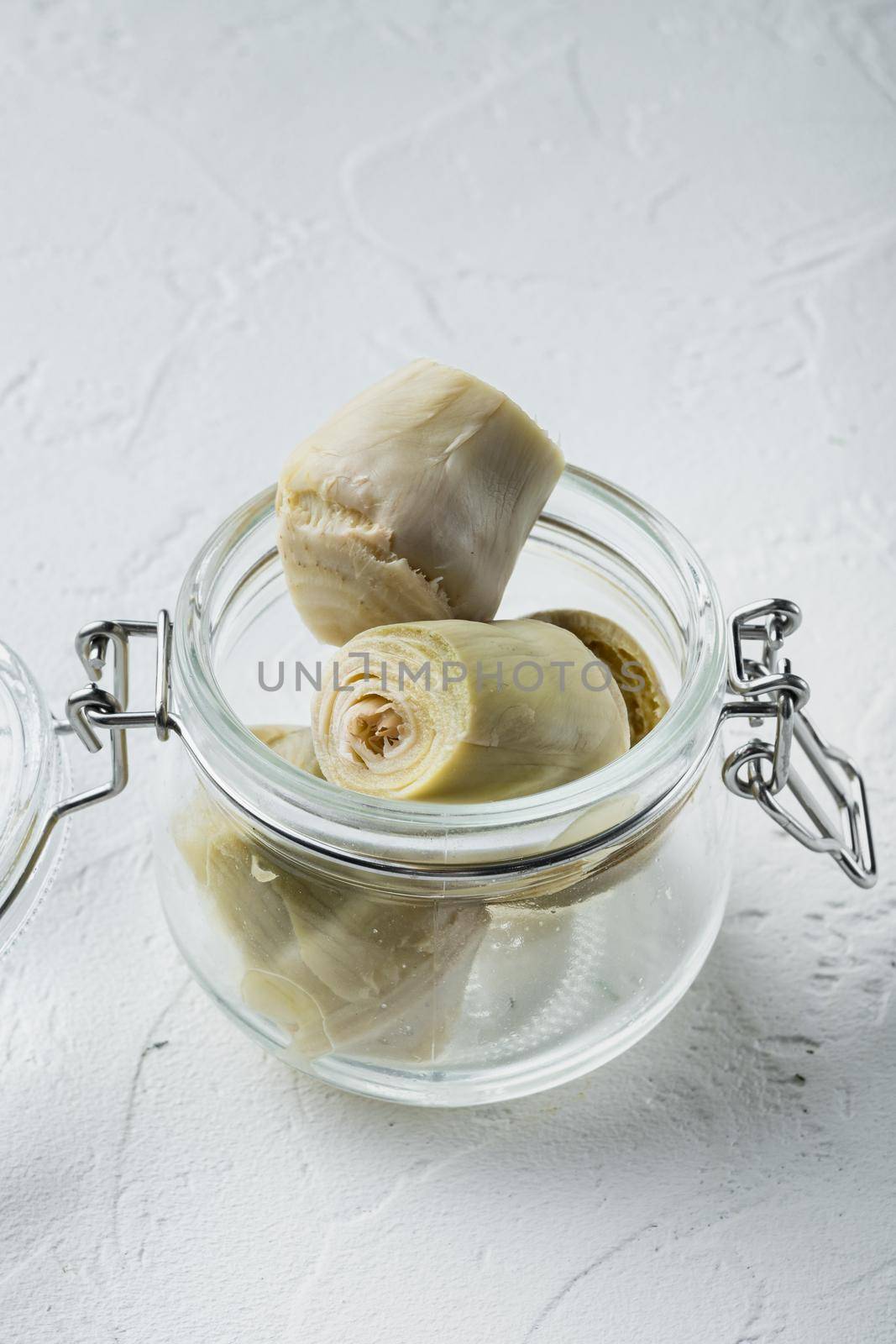 Canned artichokes with olive oil, on white textured background