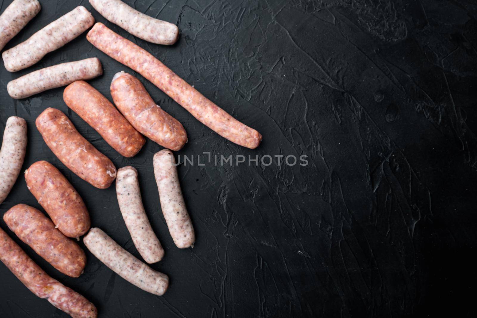 Raw homemade sausages, flat lay with space for text, on black background.