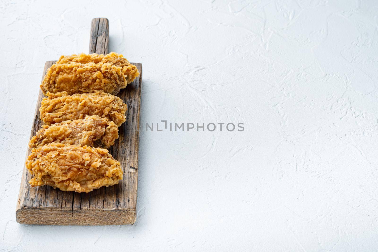 Breaded chicken wings cuts on white background, with copy space.