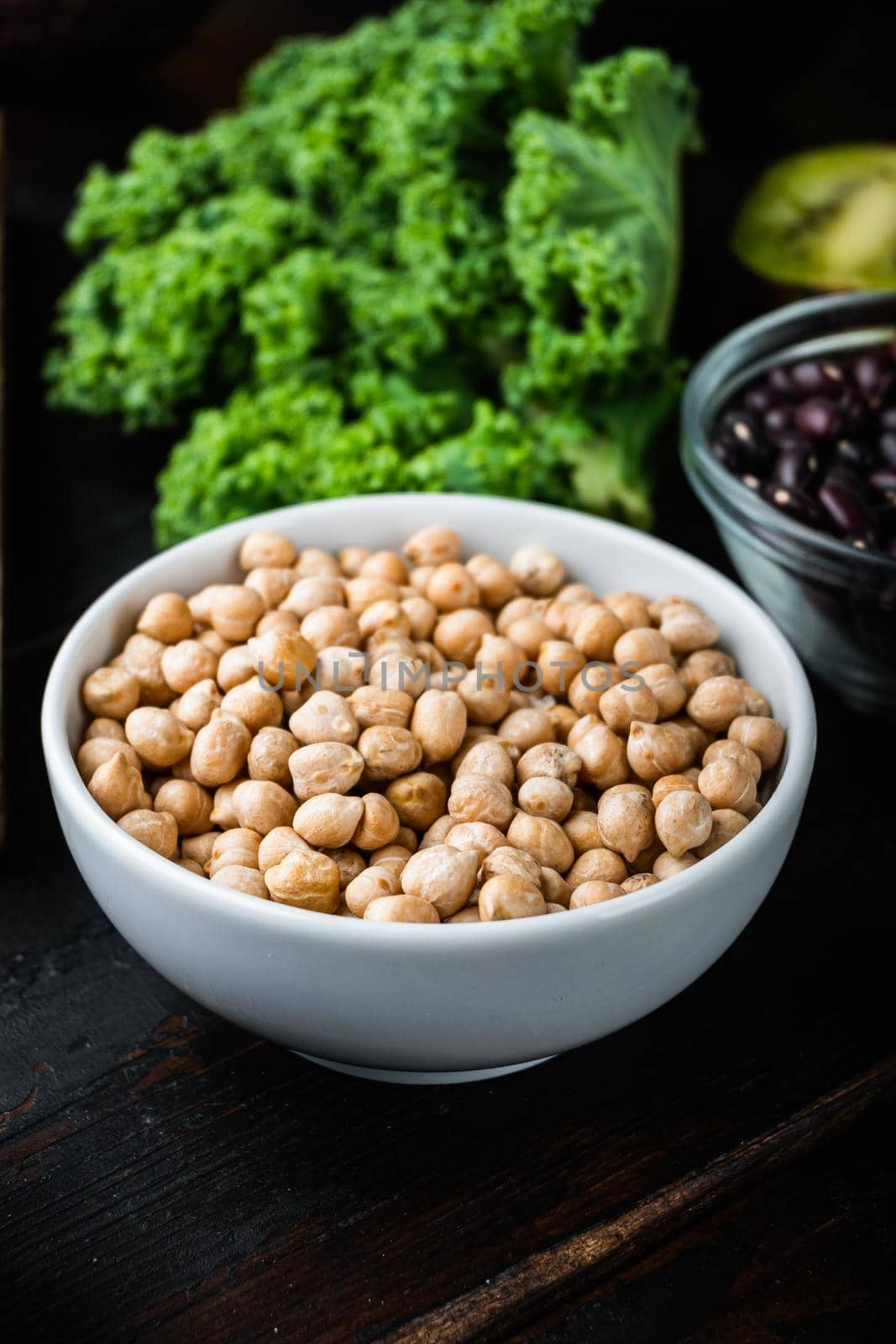 Chickpea in white bowl on dark wooden background.