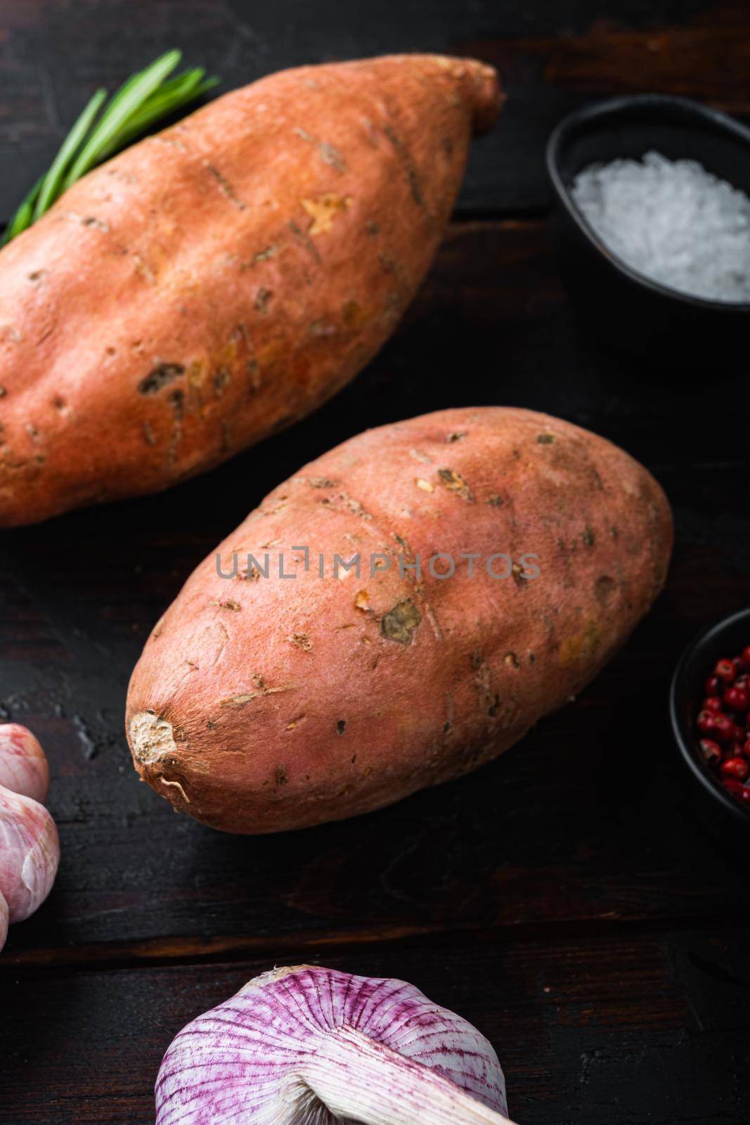 Sweet potato or batat with herbs on old wooden table.