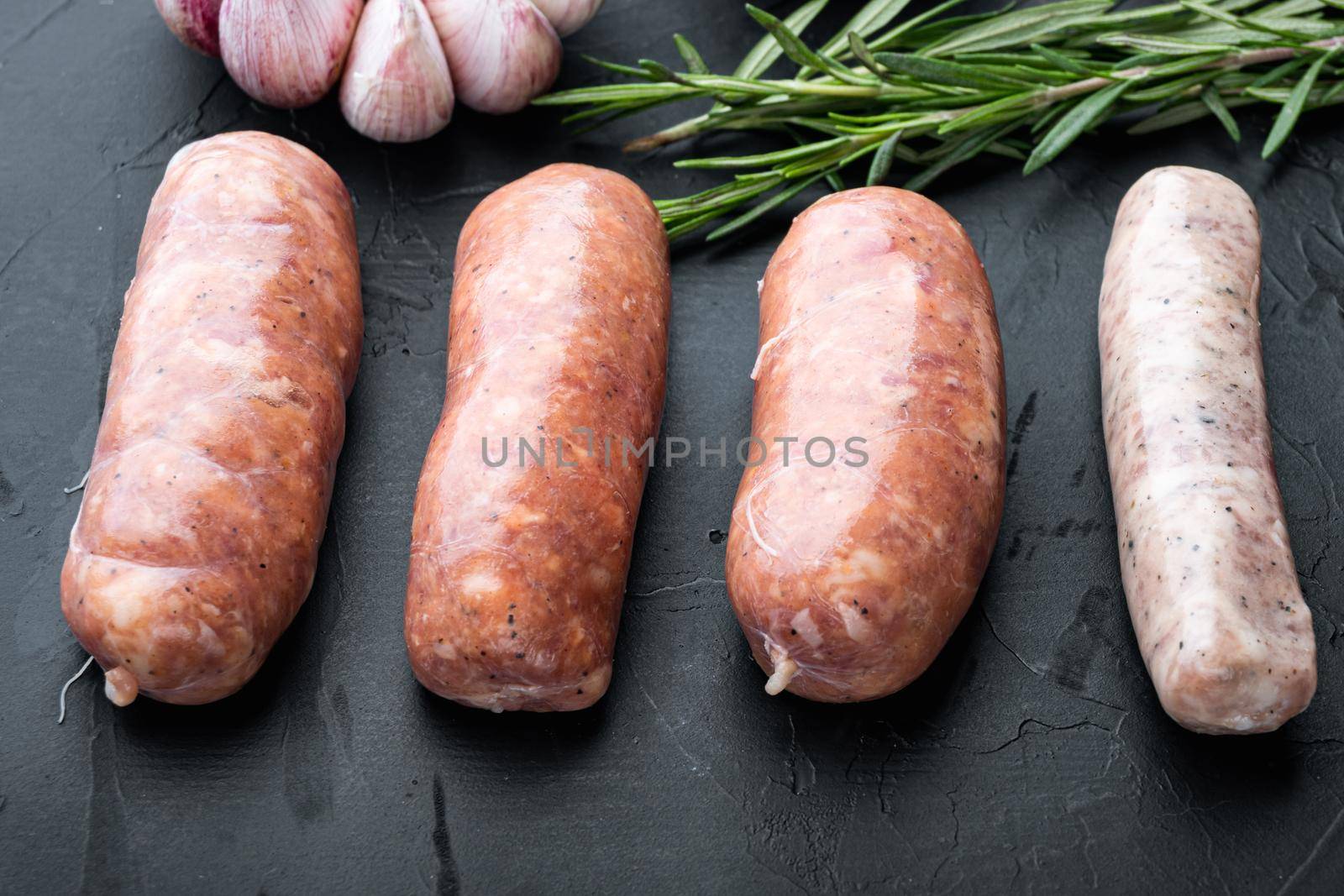 Raw homemade sausages, on black background.