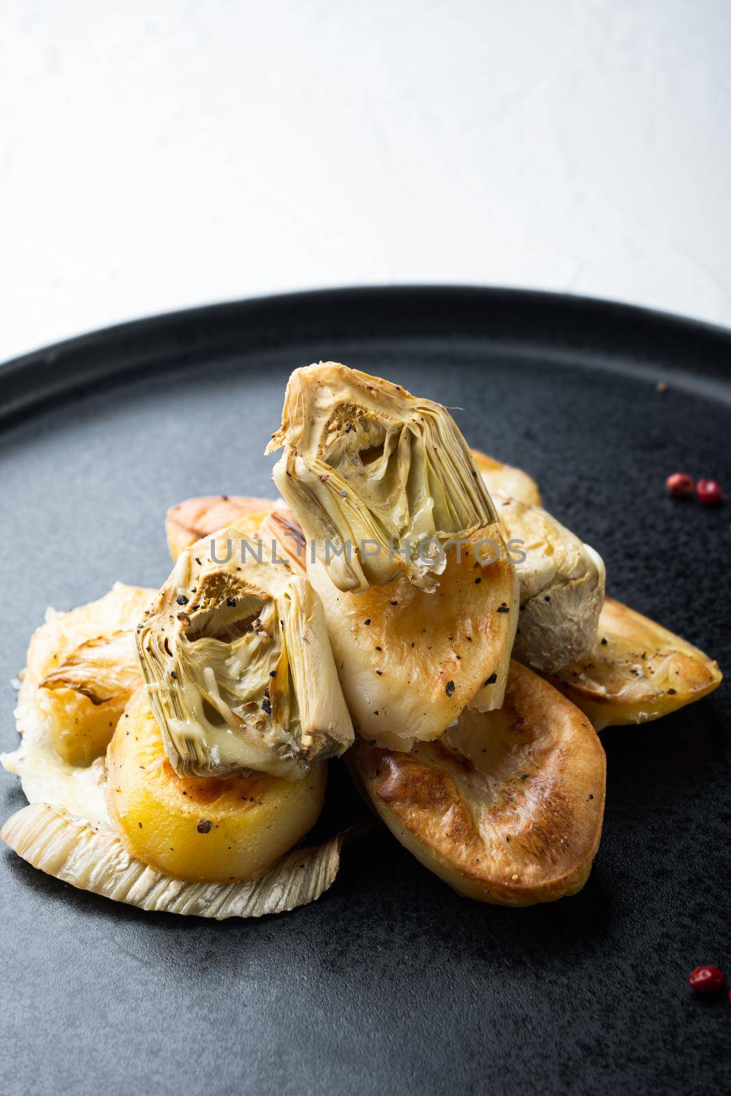 Baked potato, artichoke with fennel al forno, on white textured background